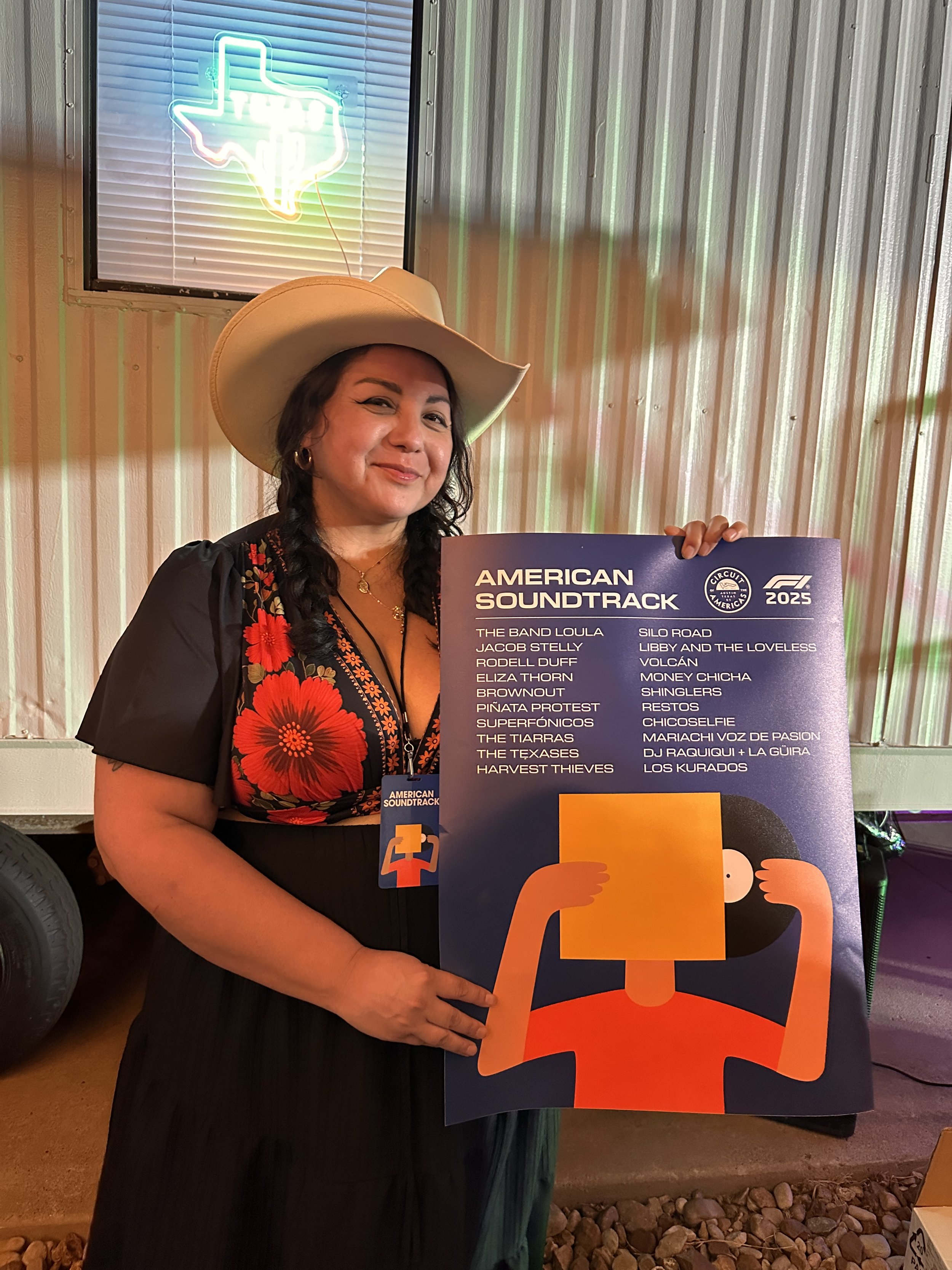 A woman wearing a cowboy hat and floral dress holding a poster promoting the American soundtrack album for Circo de Mexico 2023, with a neon Texas outline in the background.