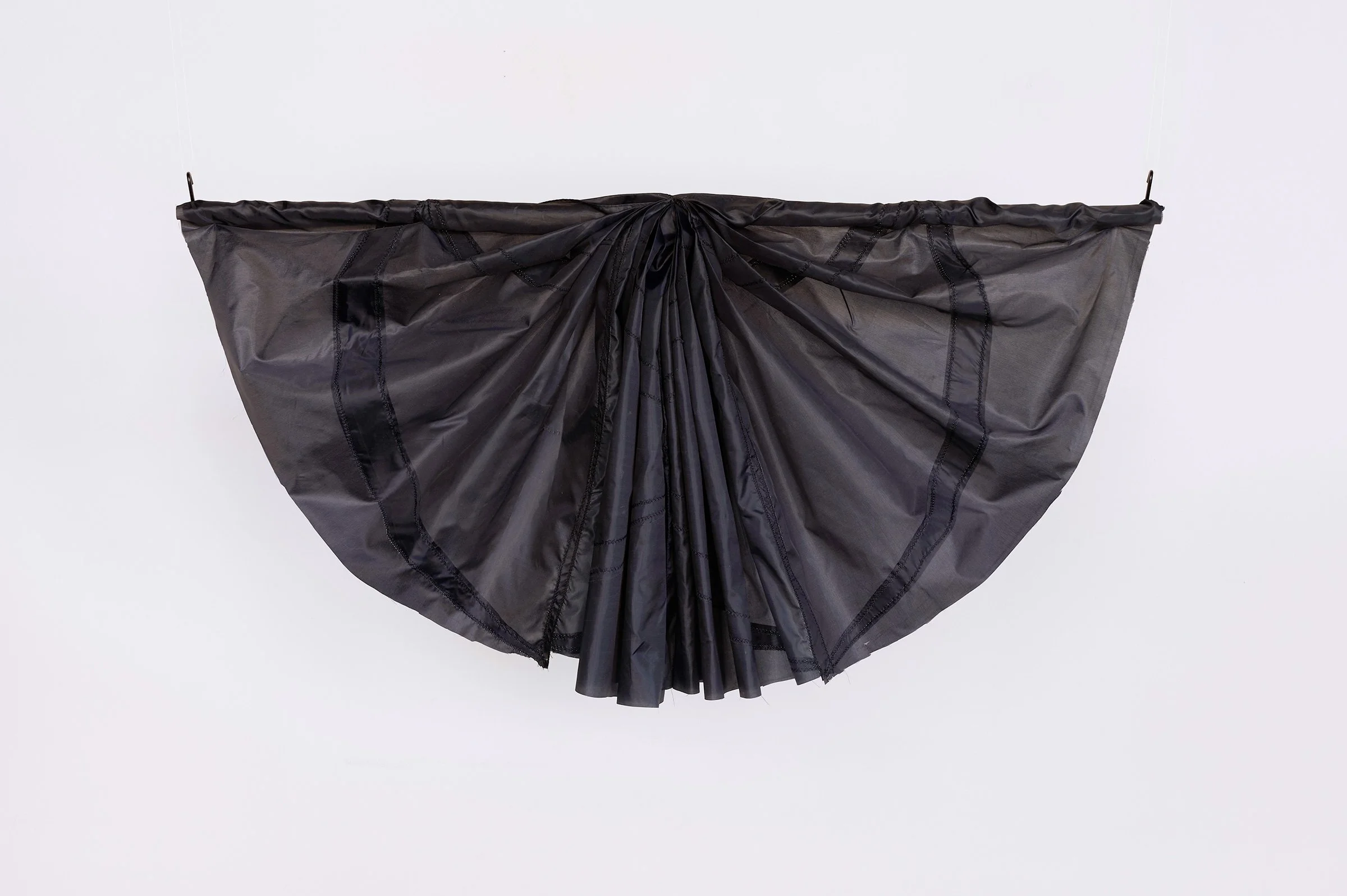 Mourning Bunting study, wall-mounted sculpture of folded black umbrella canopy fabric arranged in a fan-like shape