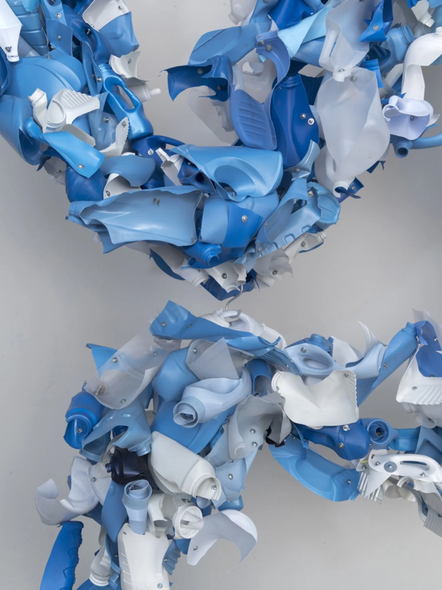 Detail view of suspended sculpture made from Downey, Ajax, vinegar, Suavitel fabric softener bottles, machine screws, hex nuts, and nylon rope