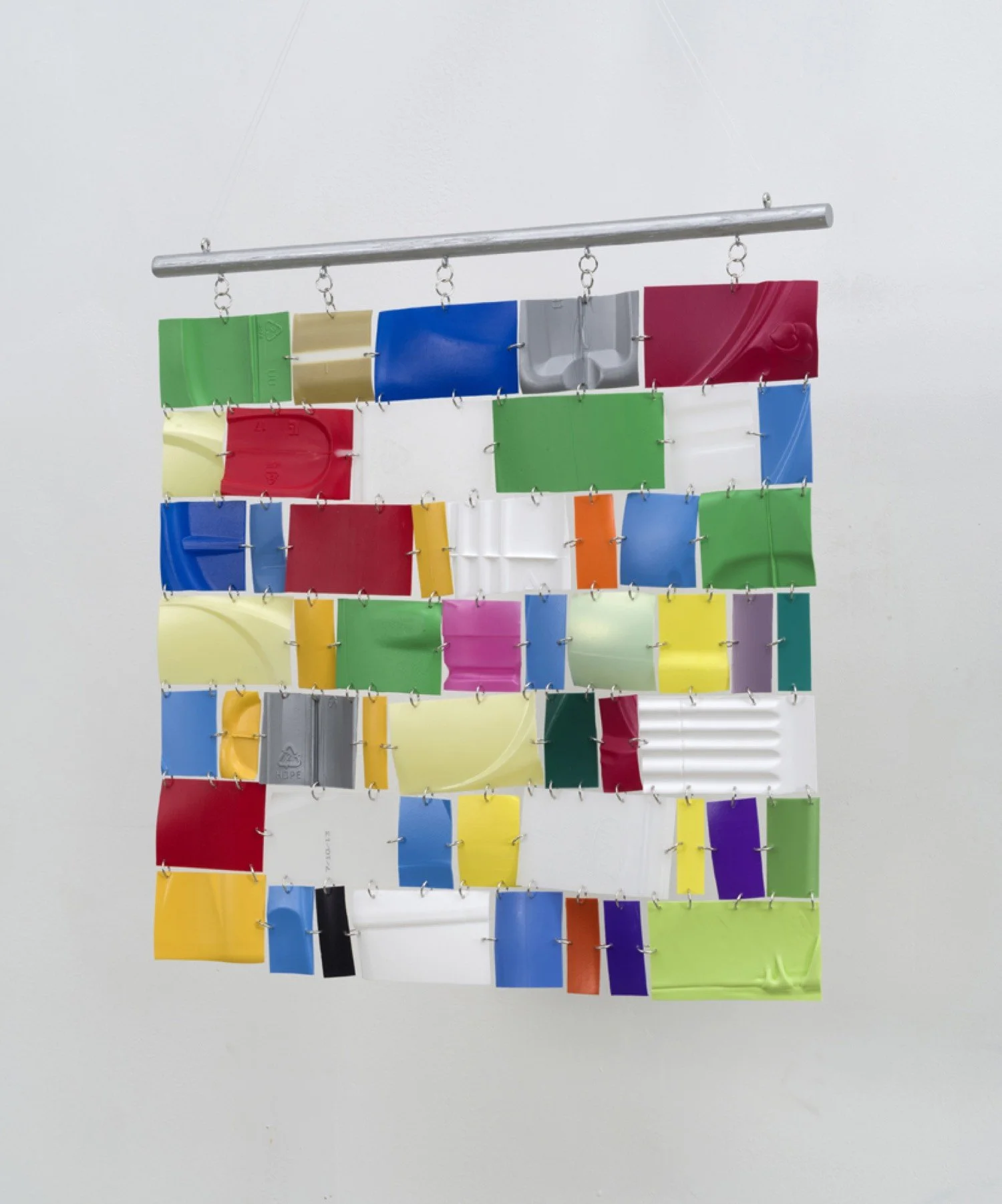Hanging wall sculpture of colorful repurposed plastic.