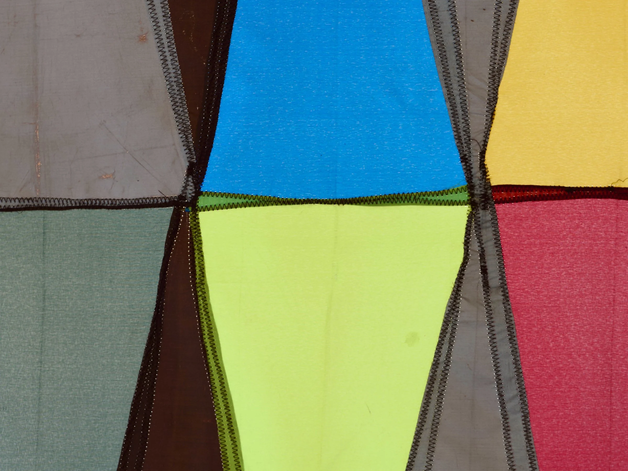 Double Digit Diptych Brown, detail view of wall-mounted textile artwork with geometric triangular panels in brown and multicolored fabric