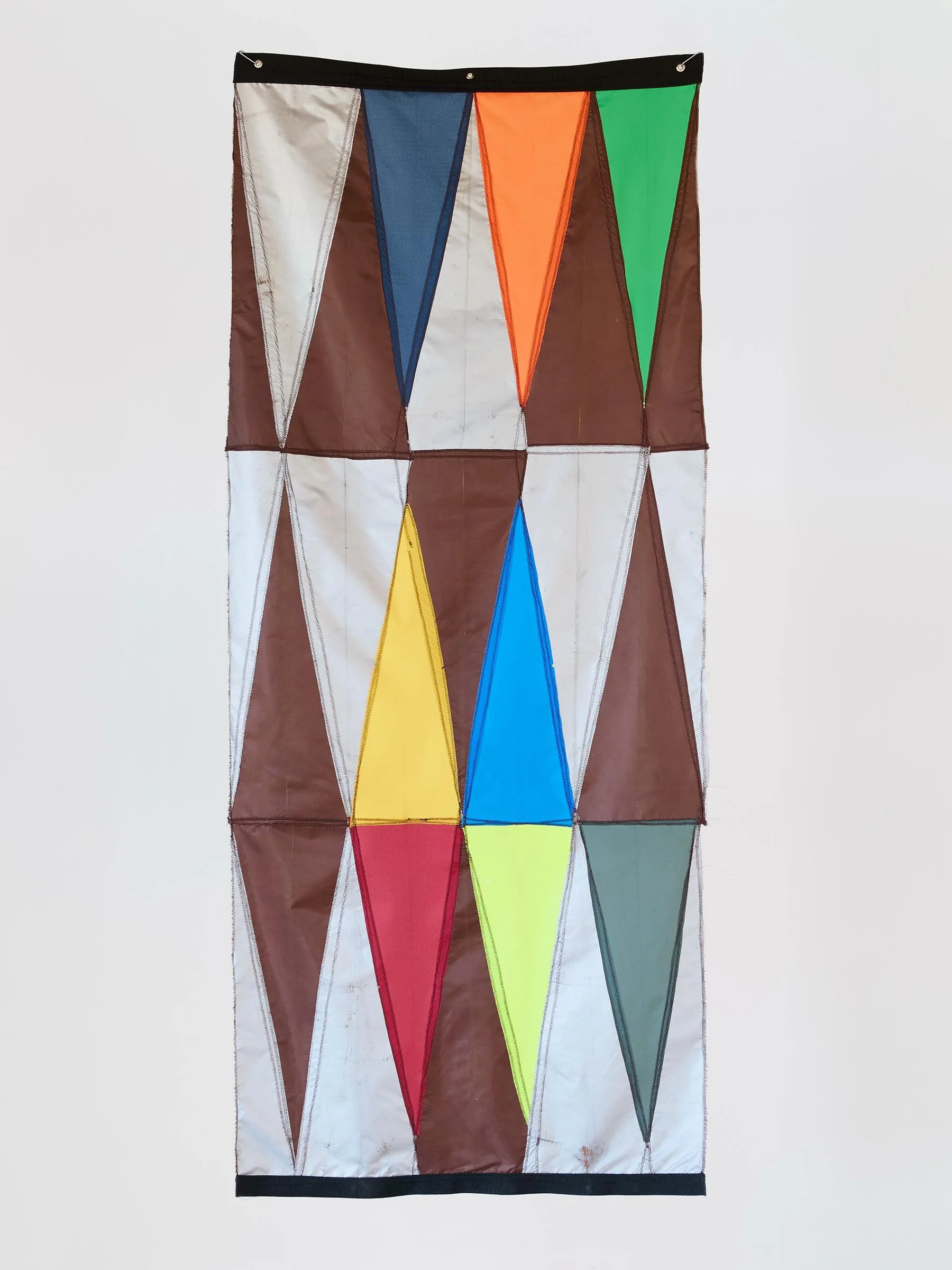 Colorful geometric pattern on fabric with zigzag shapes in various colors including white, blue, orange, green, yellow, red, gray, and brown.