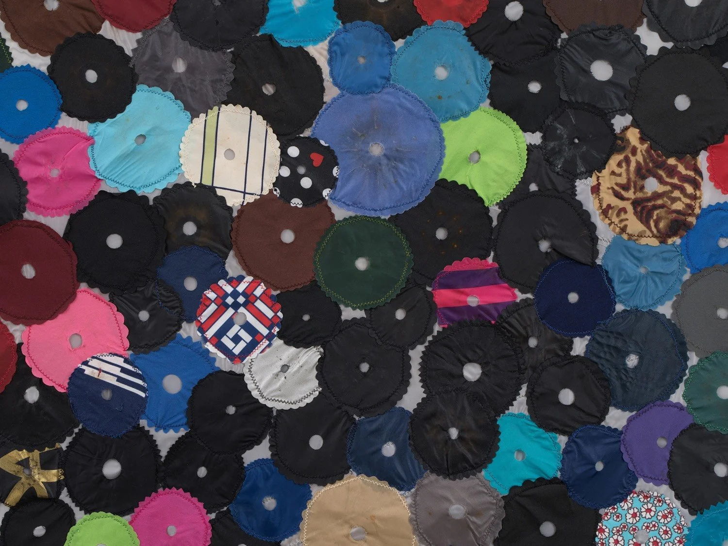 Multicolored hanging wall sculpture made with umbrella canopies, nylon thread, nylon webbing, grommets.