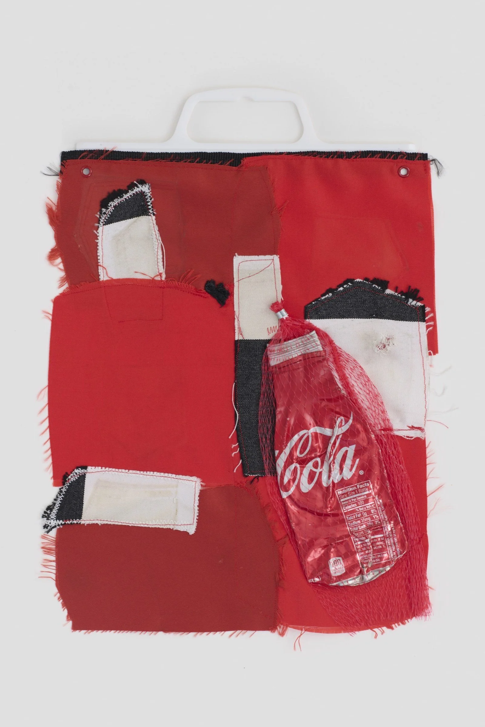 Coca is an abstract patchwork collage made of an aluminum soda can, vegetable netting, and a plastic bag handle