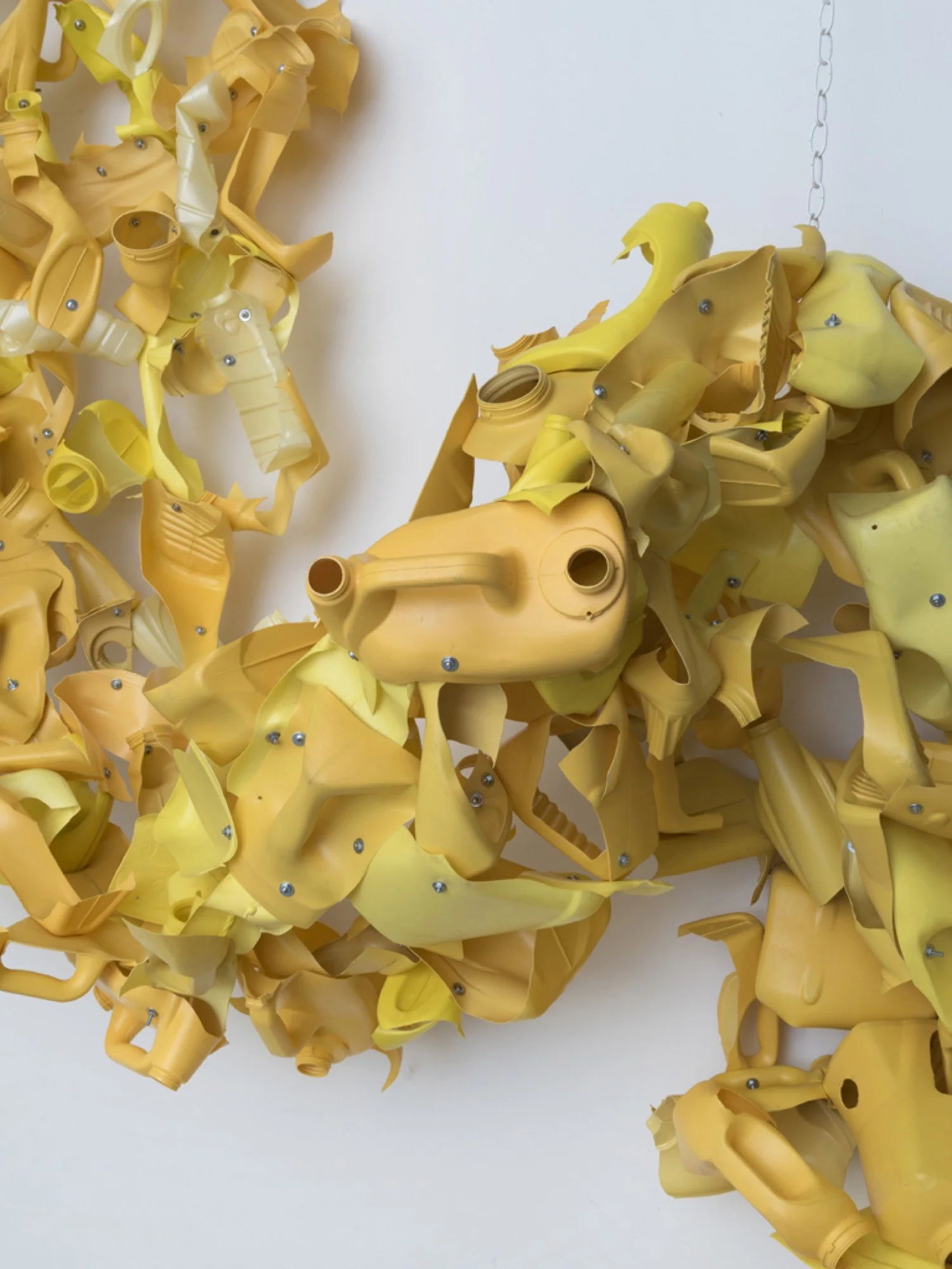 Detail of suspended sculpture made from Arm & Hammer and corn oil bottles, machine screws, hex nuts, and nylon rope