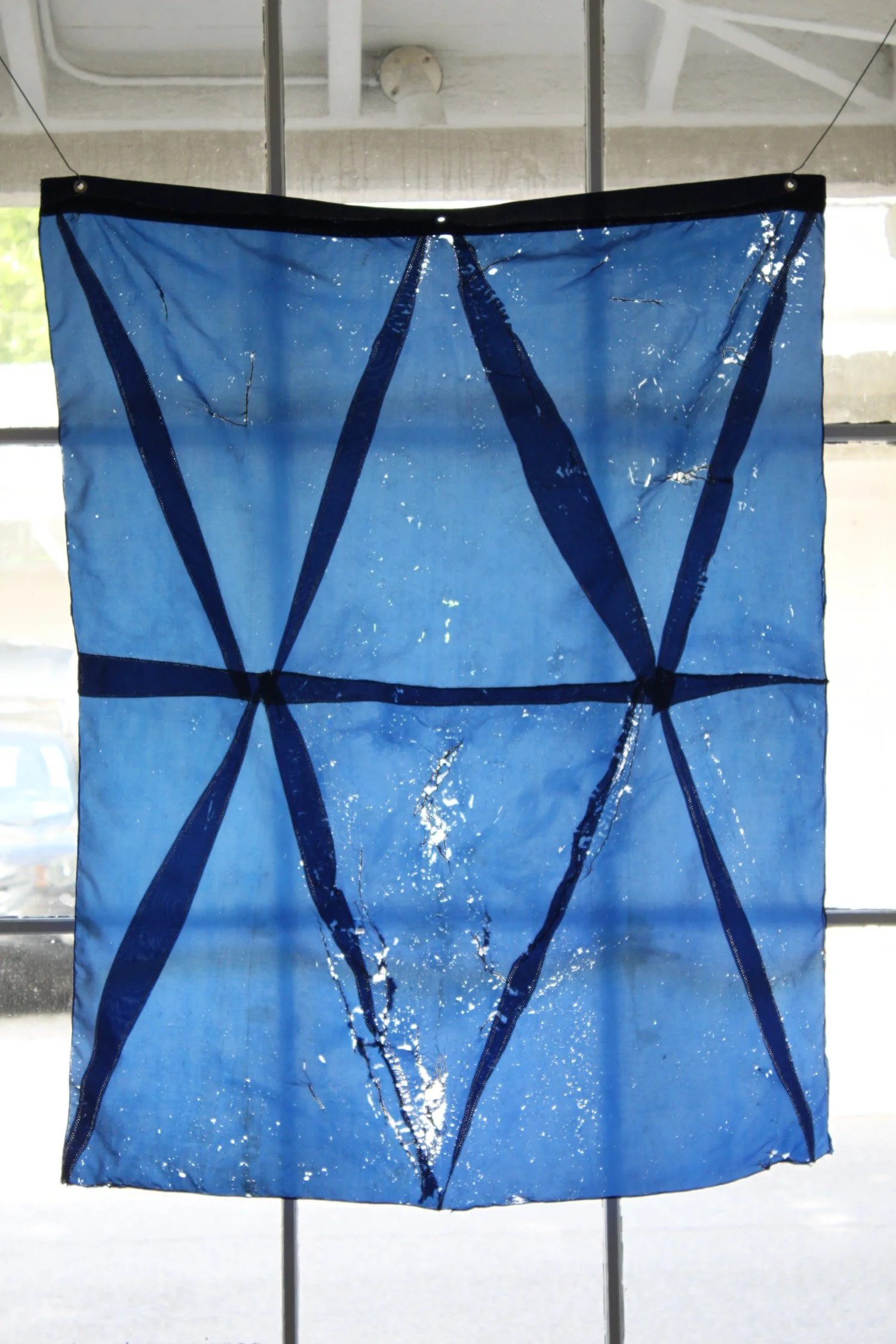Hanging sculpture made of dark colored umbrella canopies, nylon thread, nylon webbing, grommets