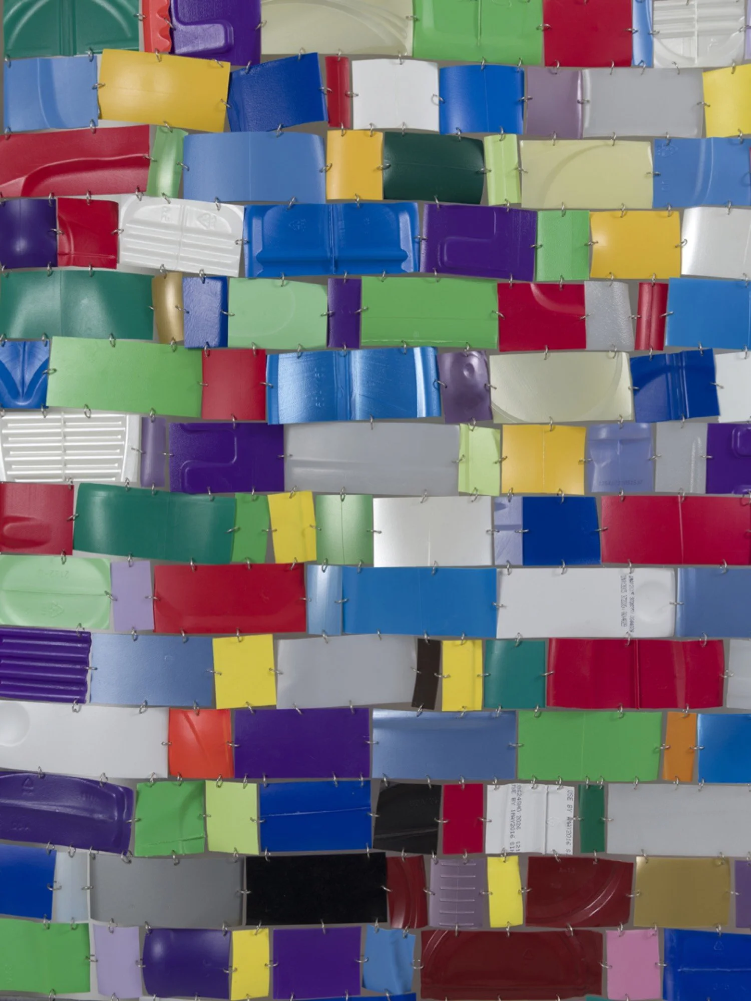 Hanging wall sculpture of colorful repurposed plastic.