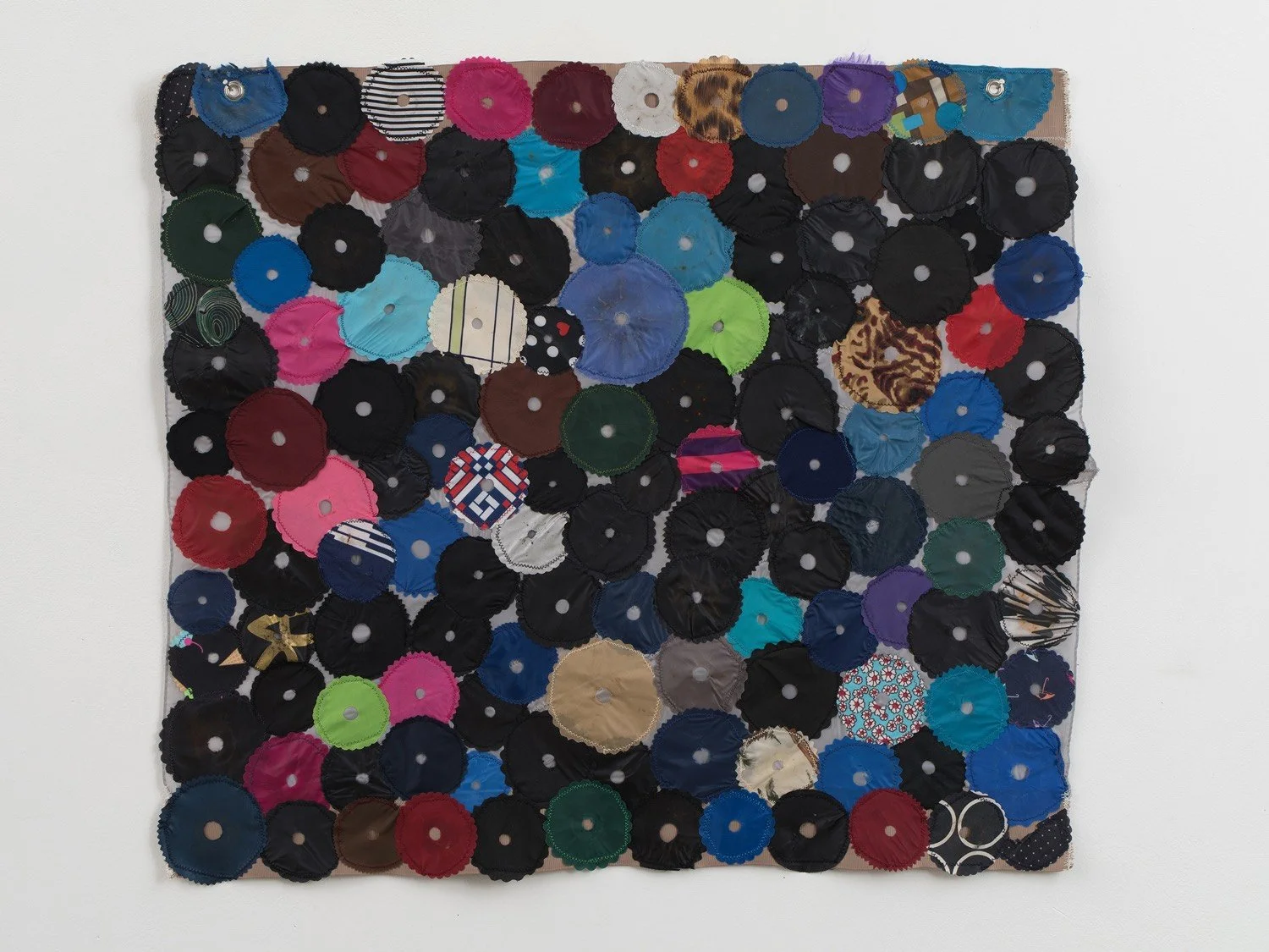 Multicolored hanging wall sculpture made with umbrella canopies, nylon thread, nylon webbing, and grommets.