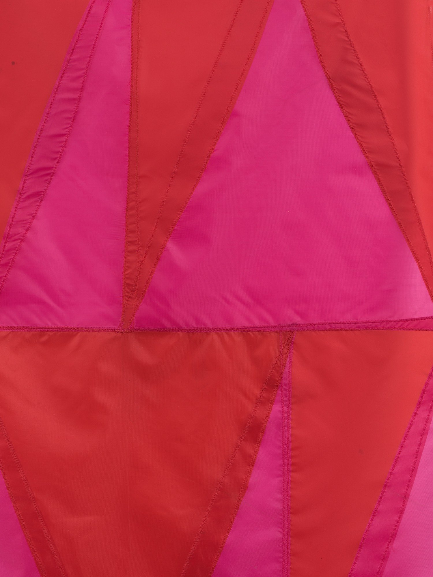 Red and pink hanging wall sculpture made with umbrella canopies, nylon thread, nylon webbing, and grommets.