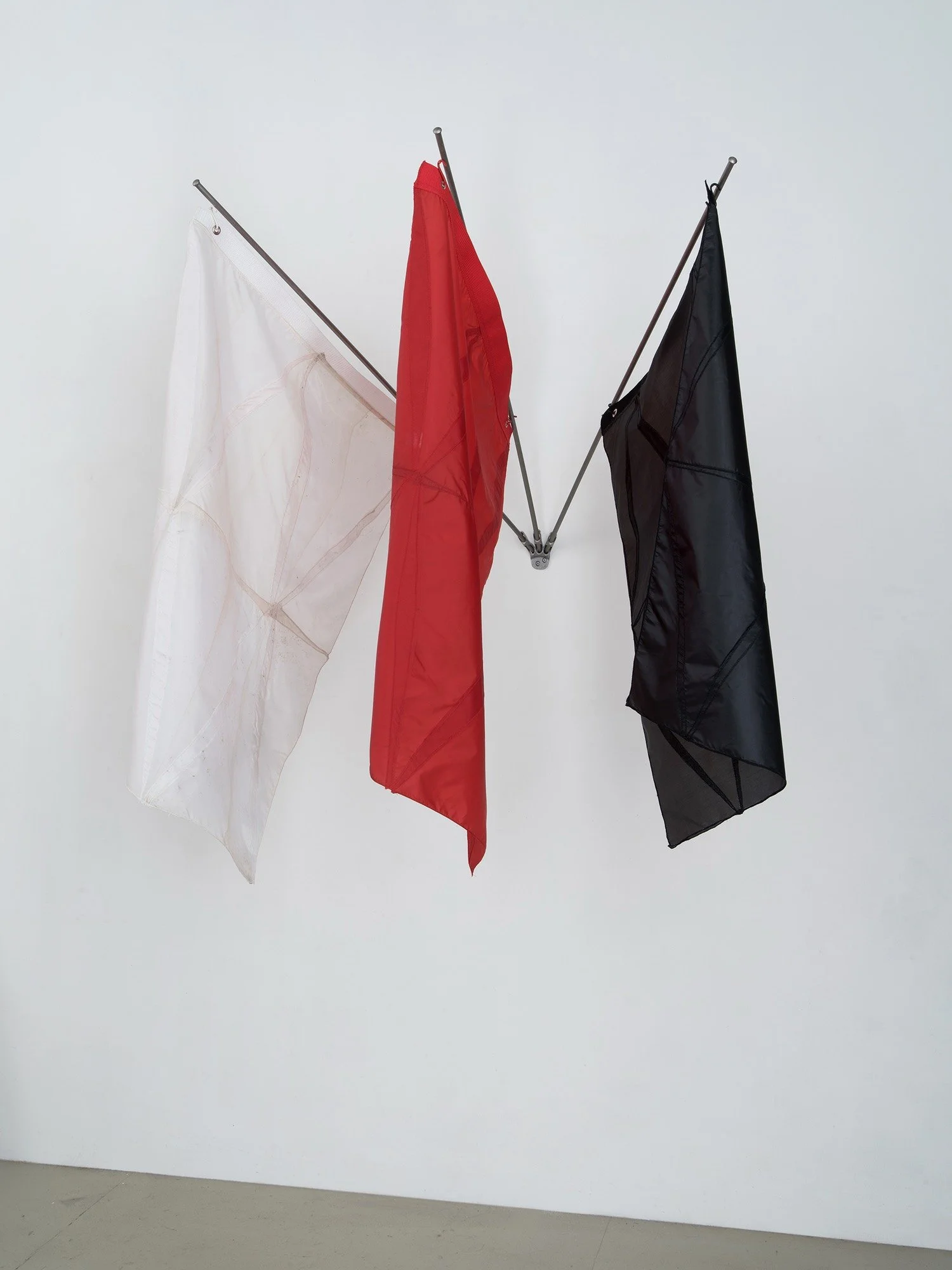 Hanging sculpture made of dark colored umbrella canopies, nylon thread, nylon webbing, grommets