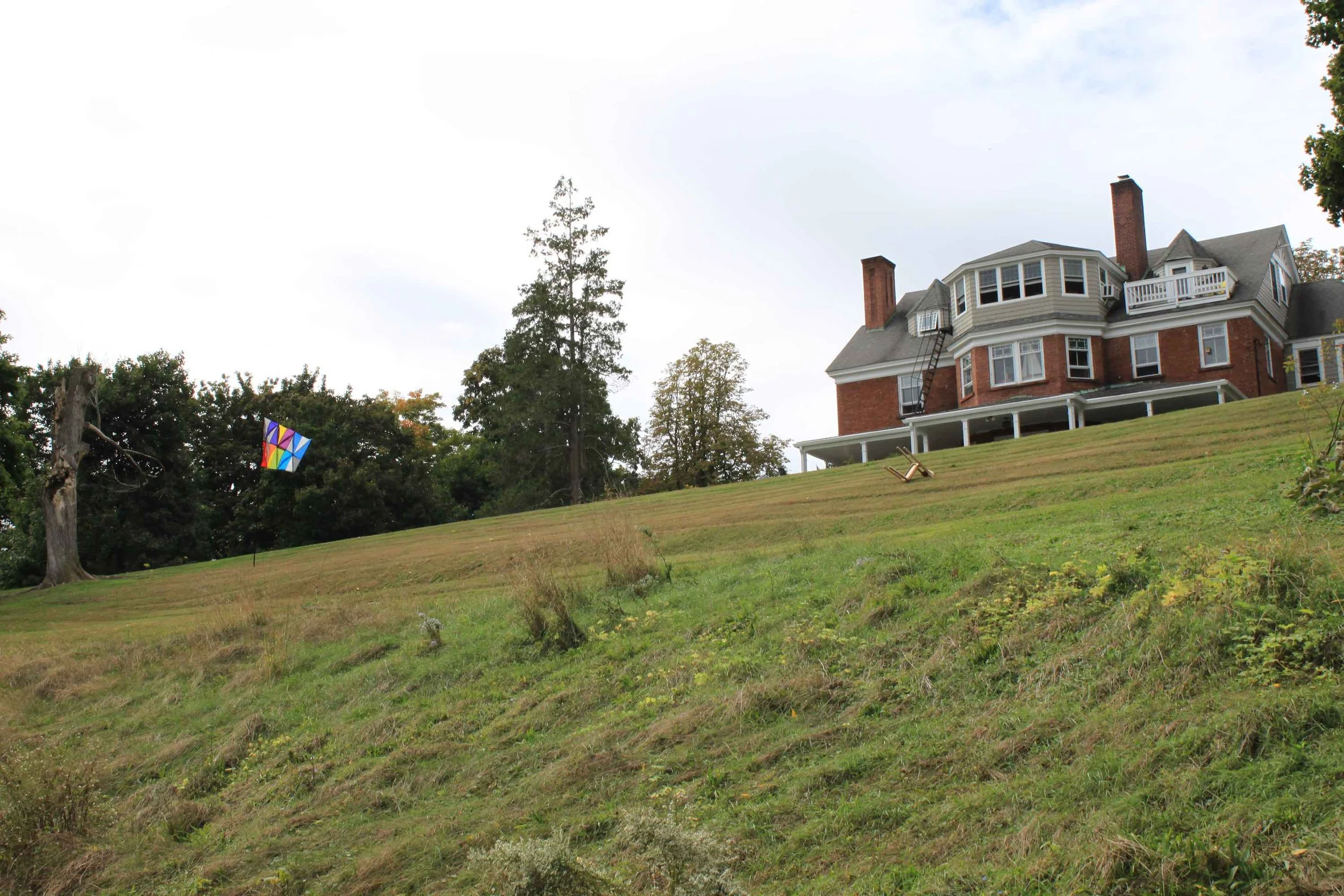 Multicolored flag sculpture installed outdoors along sloping hillside.