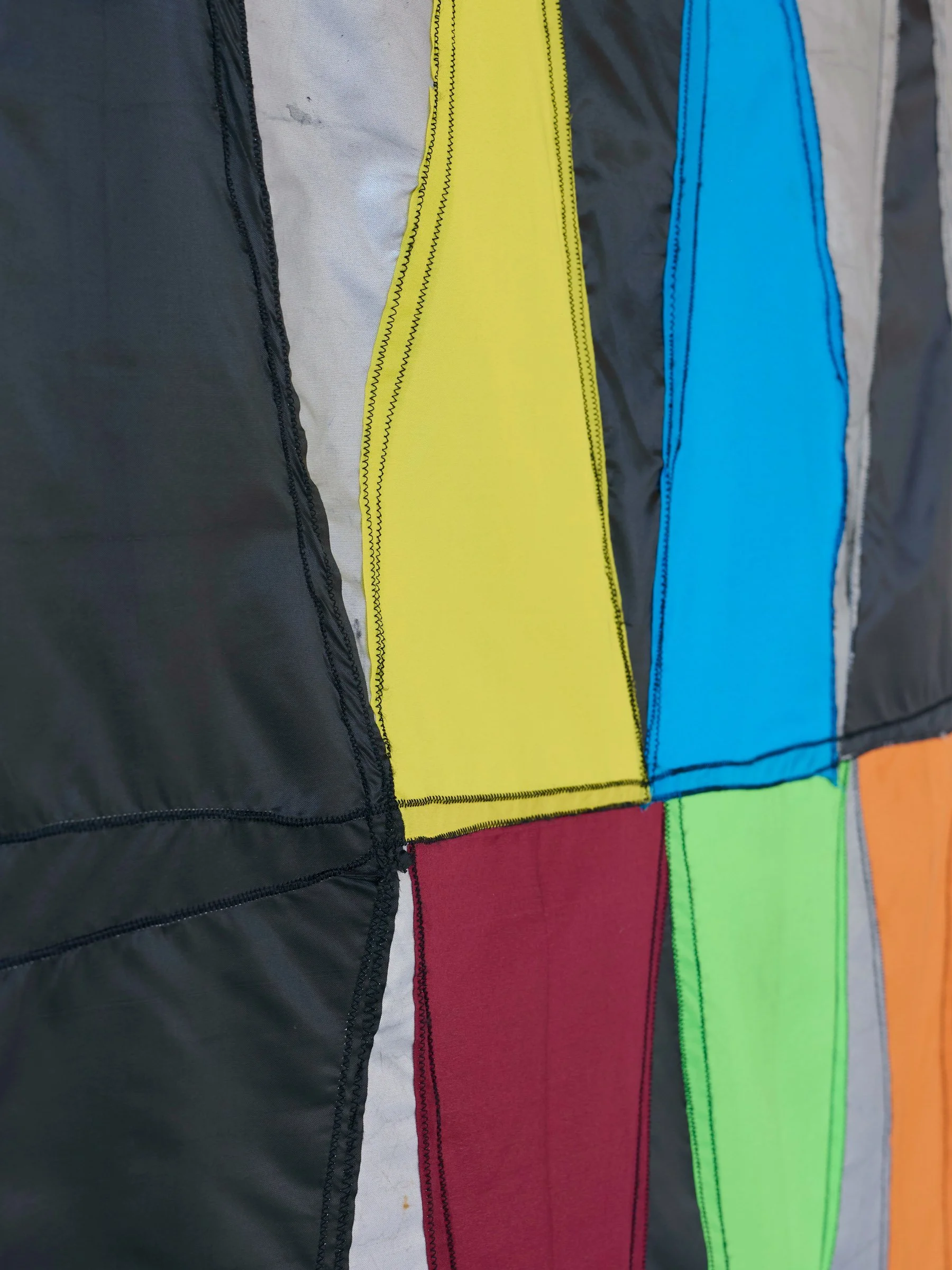 Double Digit Diptych Black, detail view of wall-mounted textile artwork with geometric triangular panels in black and multicolored fabric
