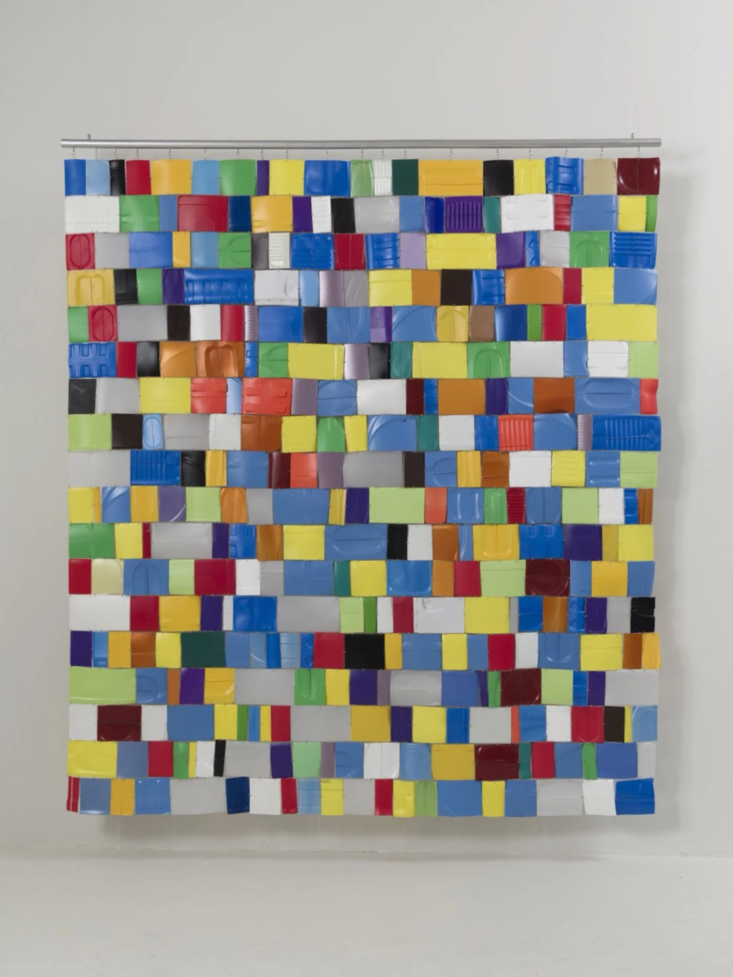 Multicolored recycled plastic bottles, wire fasteners, wood dowel, acrylic paint.