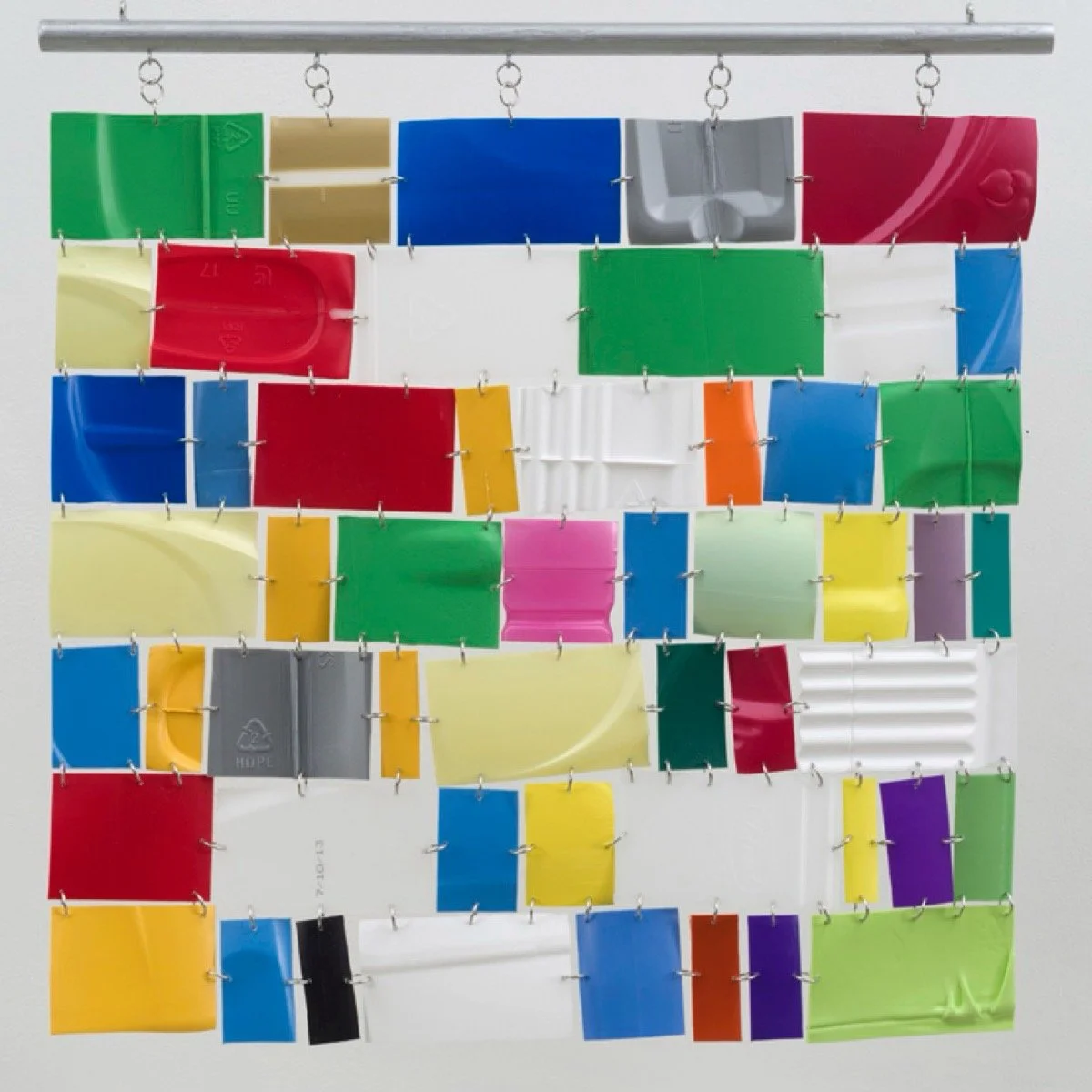 Hanging wall sculpture of colorful repurposed plastic.
