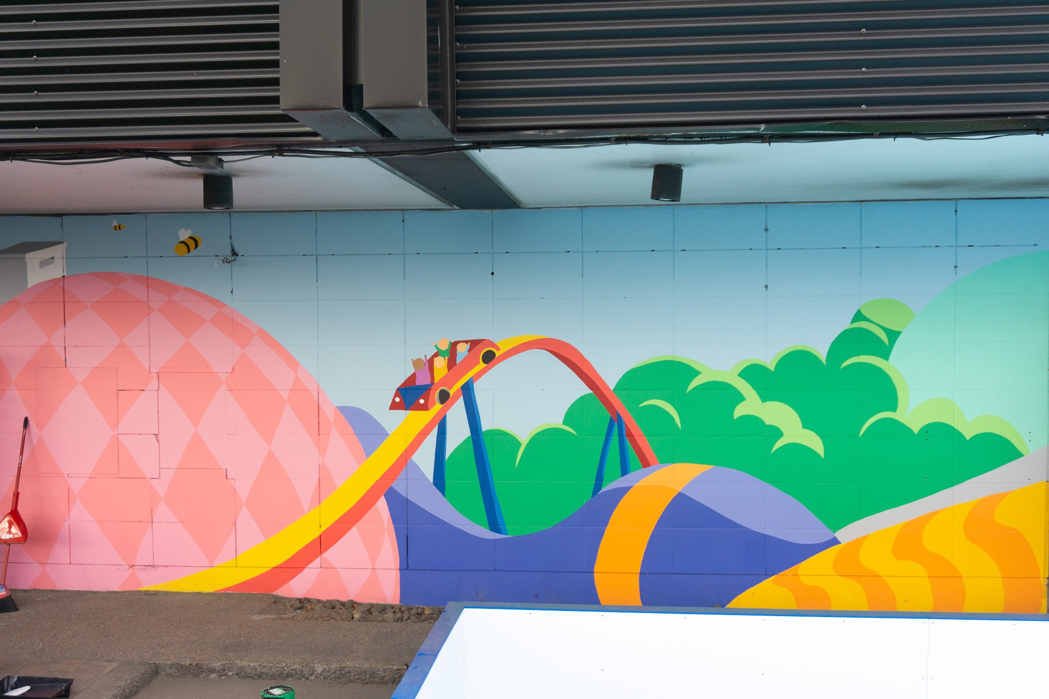 Peinture murale pour hotel ruby foo's à montréal colorée avec montagnes et montagnes russes, abeille et ciel bleu. Fait par edgar vachon-desautels muraliste.