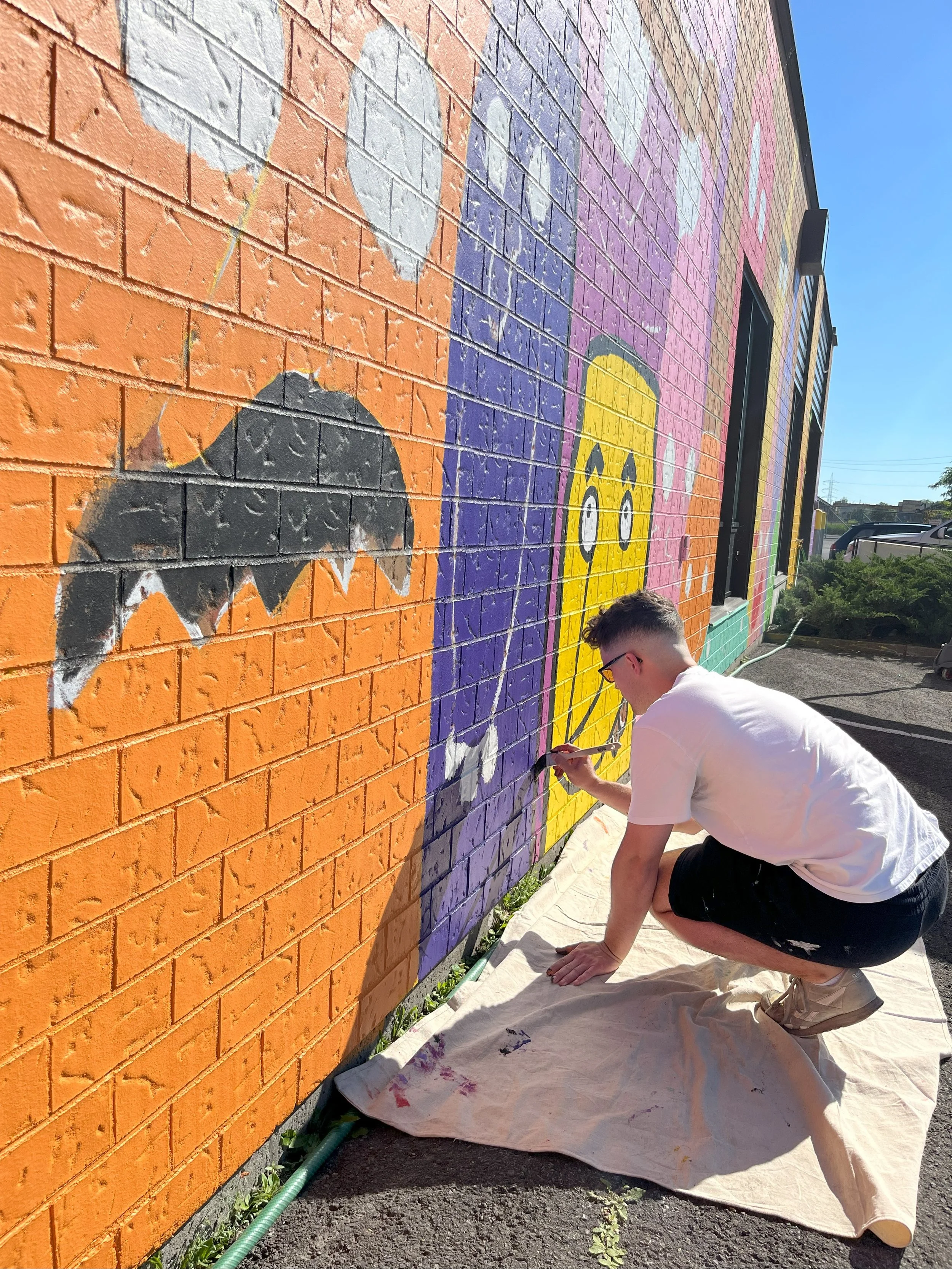 edgar artiste muraliste entrain de peindre la murale exterieur la famille des verres à candiac