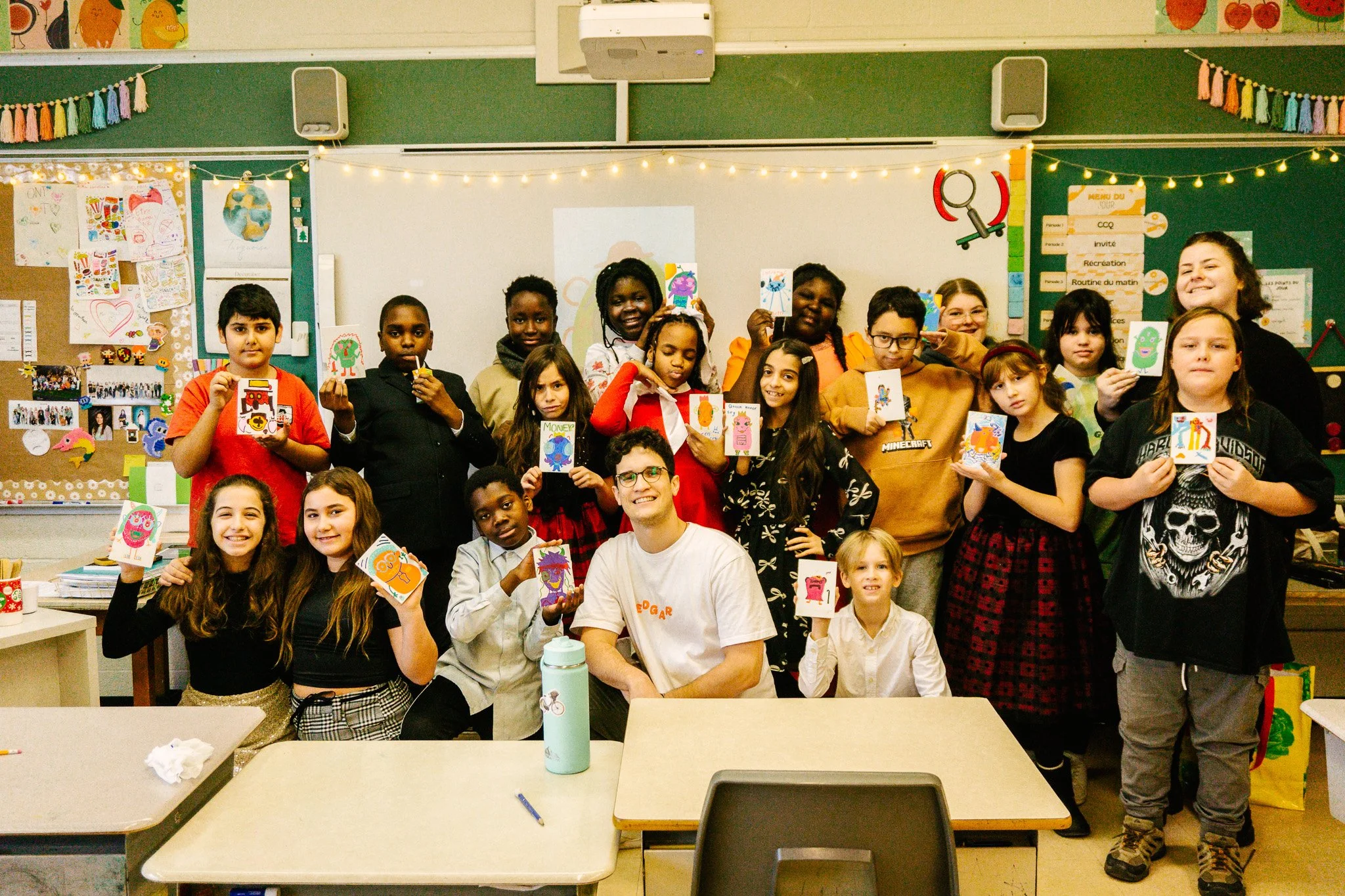 Groupe d'enfants et un adulte posant en classe avec des dessins colorés. Atelier fait par edgar artiste peintre pour l'école primaire jean 23