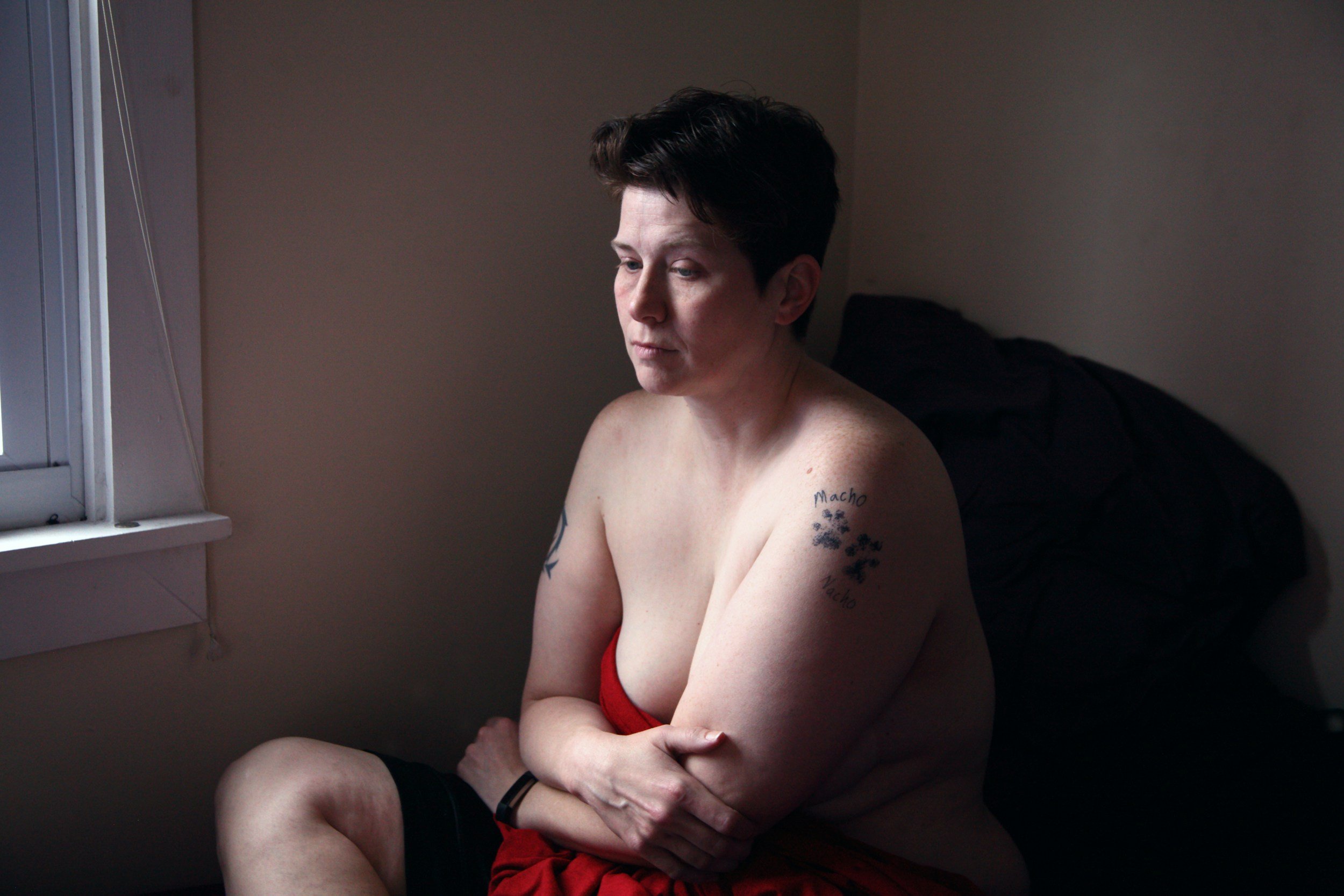 a person partially undressed in bed looking sad and disappointed