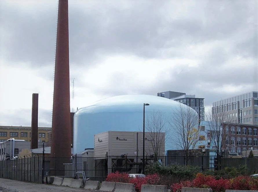 Large blue industrial dome and smokestack in urban setting