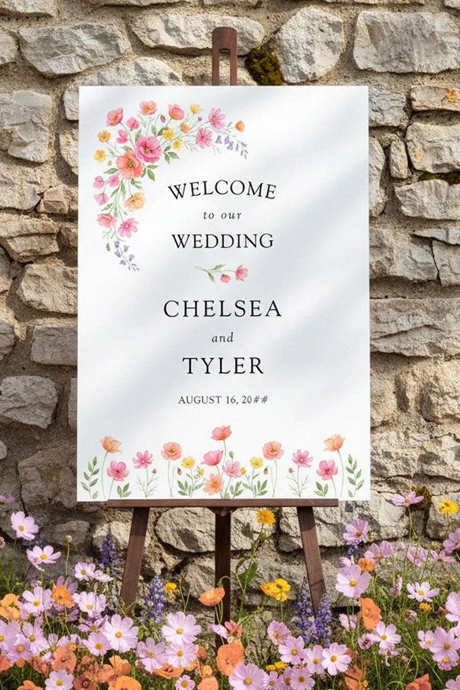 Wildflower bloom wedding welcome board on an easel in a border of flowers