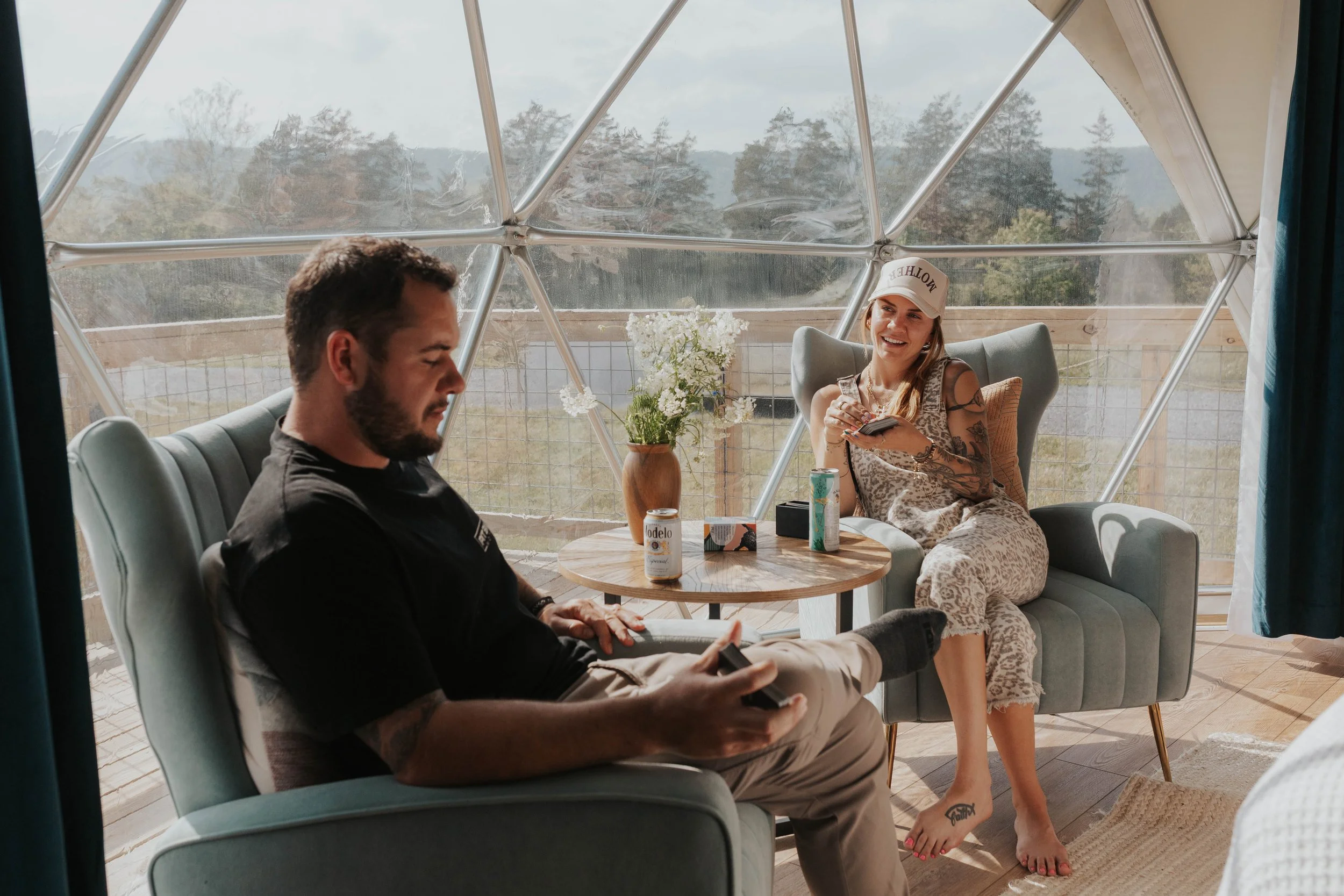 2 guests sit on chairs inside a geodesic dome