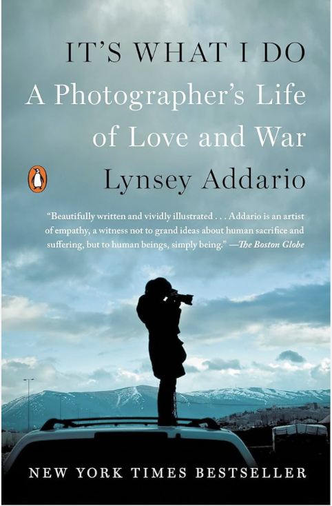 Book cover titled 'It's What I Do: A Photographer's Life of Love and War' by Lynsey Addario, featuring a silhouette of a photographer with a camera on a vehicle against a cloudy sky and mountain background, with the Penguin logo and a quote from The Boston Globe.