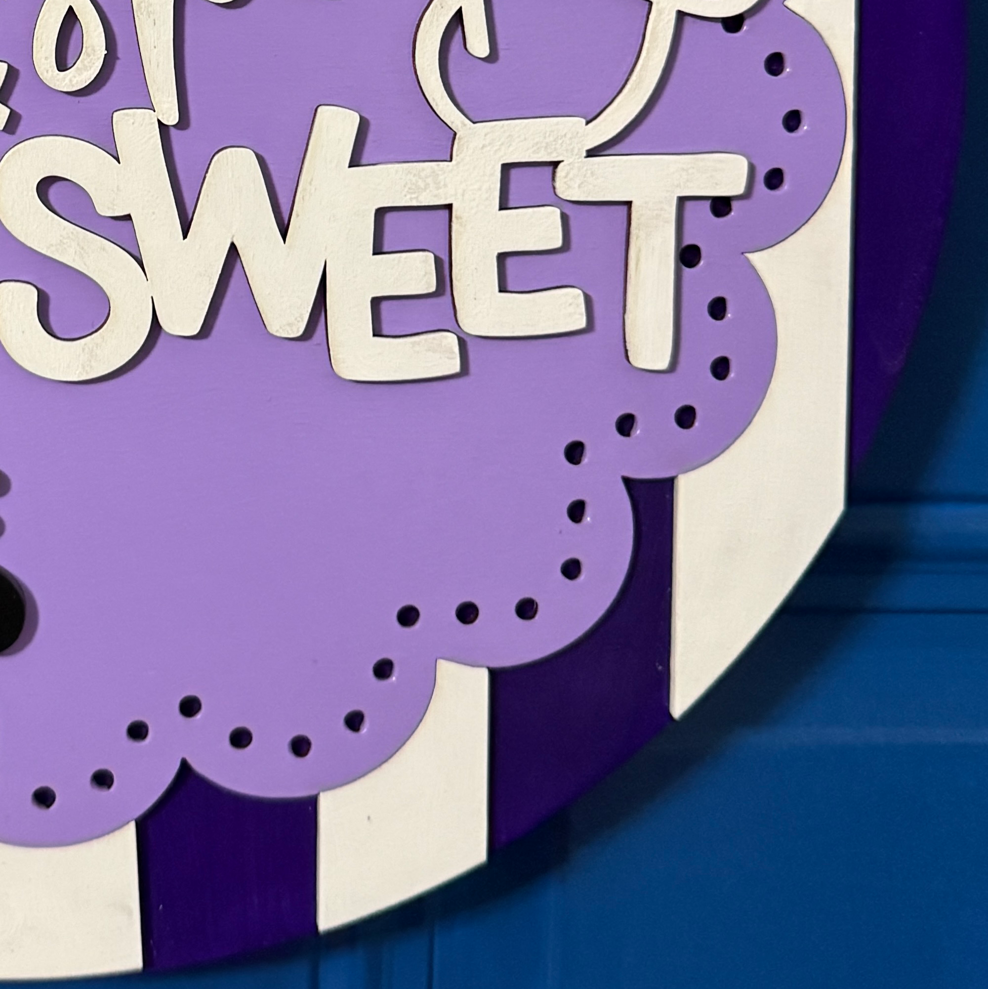 Close-up of dimensional black cat with purple eyes and accents on purple striped Halloween door hanger