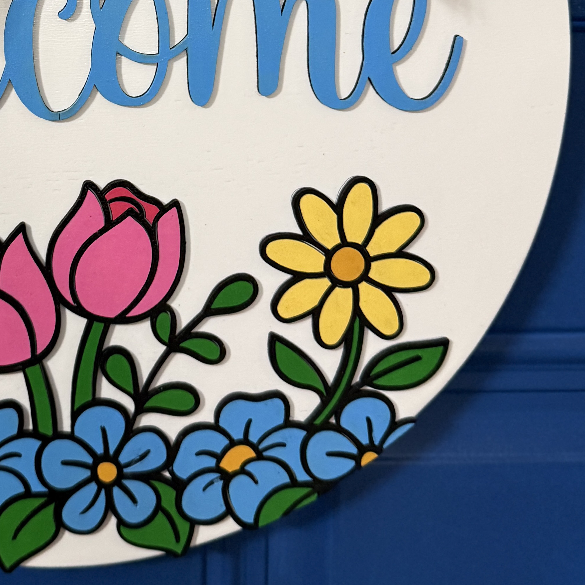 Detailed view of pink tulips and blue blossoms along bottom edge of Welcome spring front door decor
