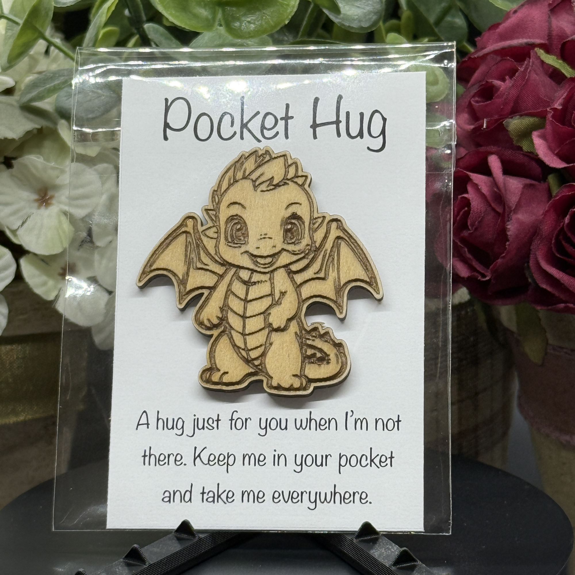 Silly Dragon Pocket Hug token on printed card – playful pose with tongue sticking out, floral background