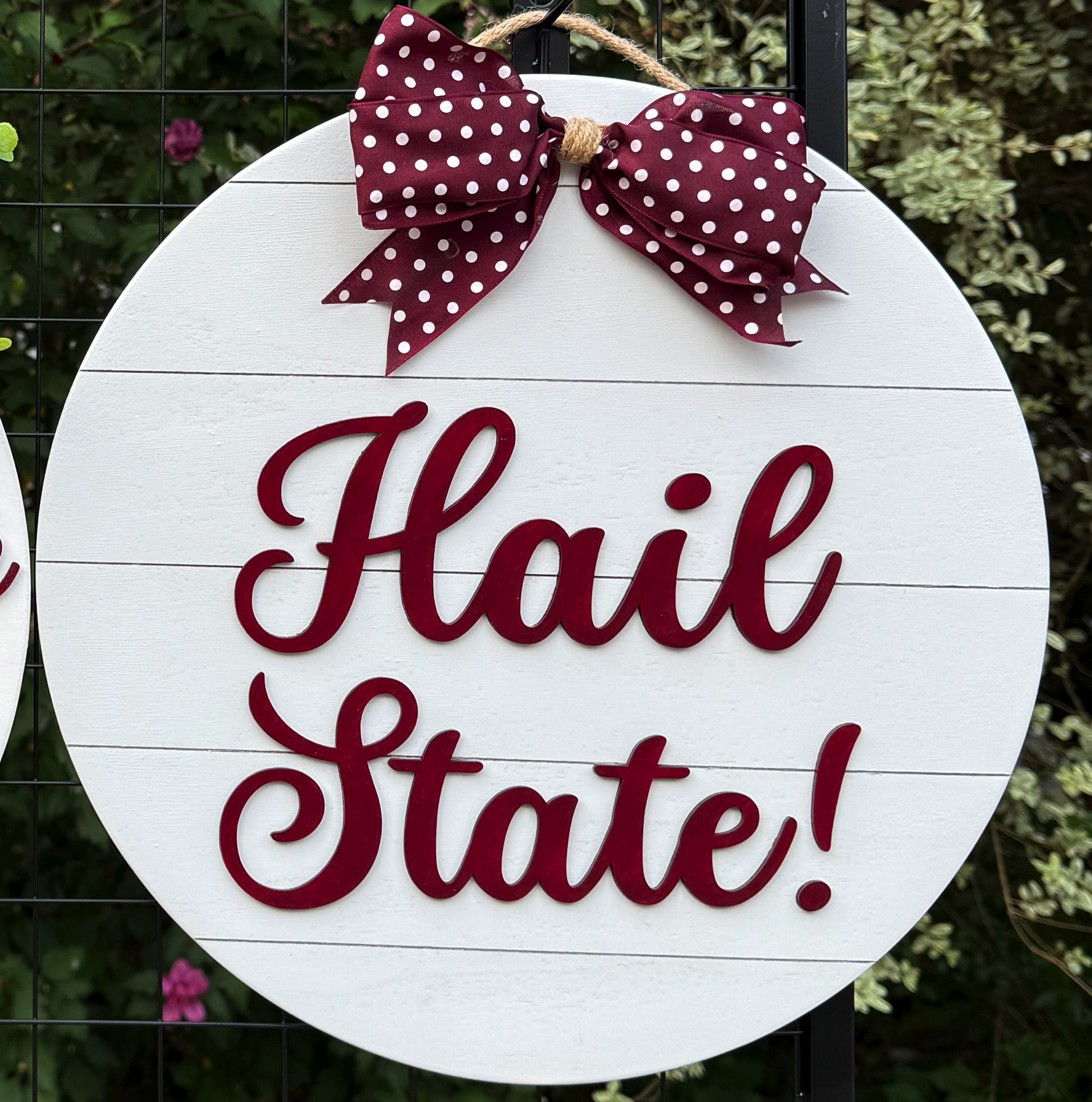 Round Hail State door hanger with bold maroon script on white shiplap background and maroon polka-dot bow