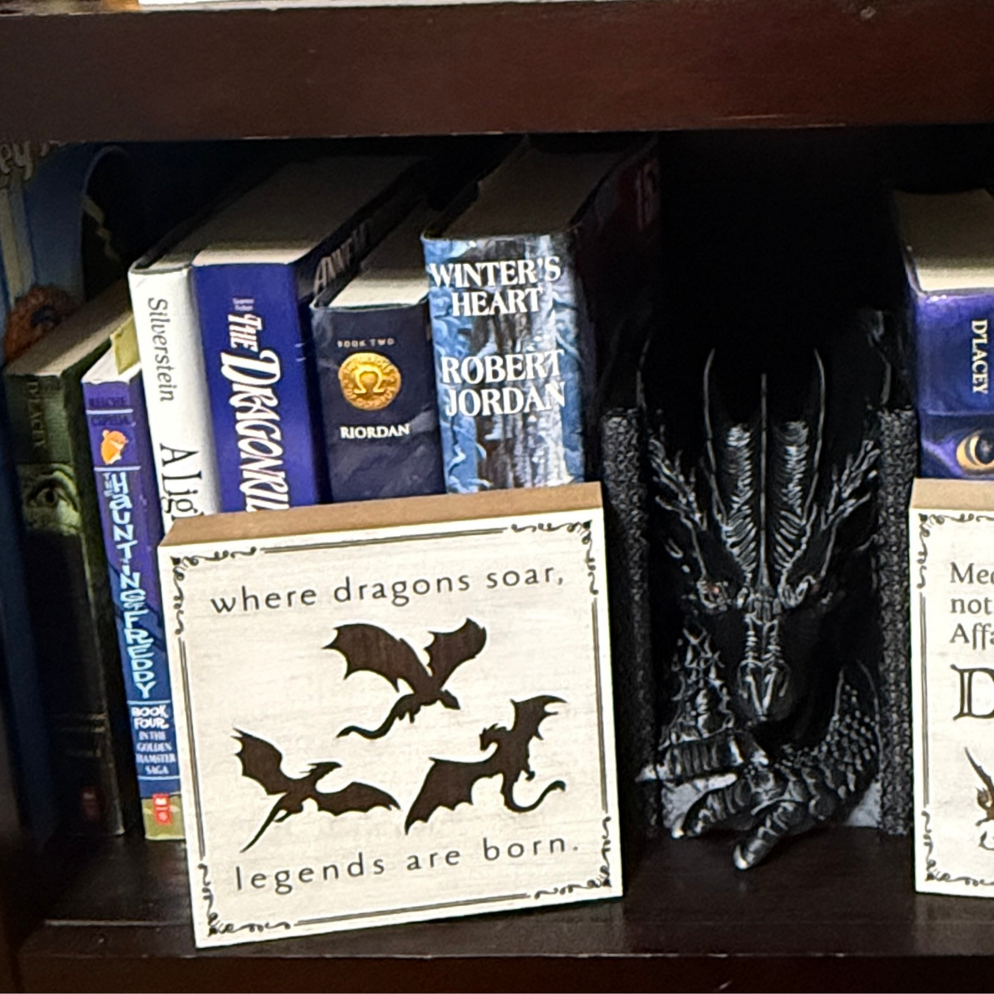 Close up of wooden where dragons soar legends are born sign with dragon silhouettes displayed between books