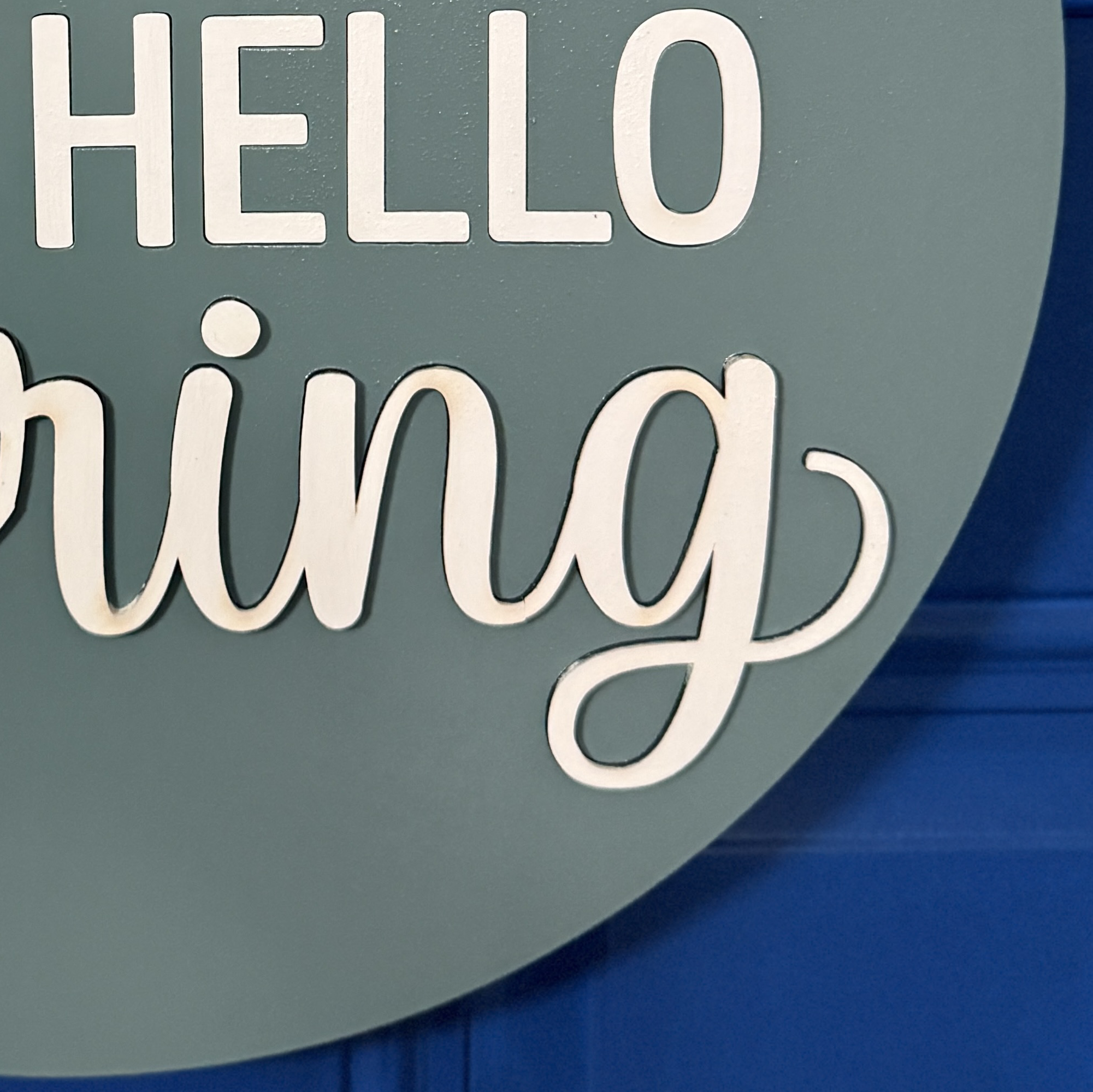 Close-up of dimensional white “HELLO” and “Spring” lettering on hand-painted patina blue door hanger