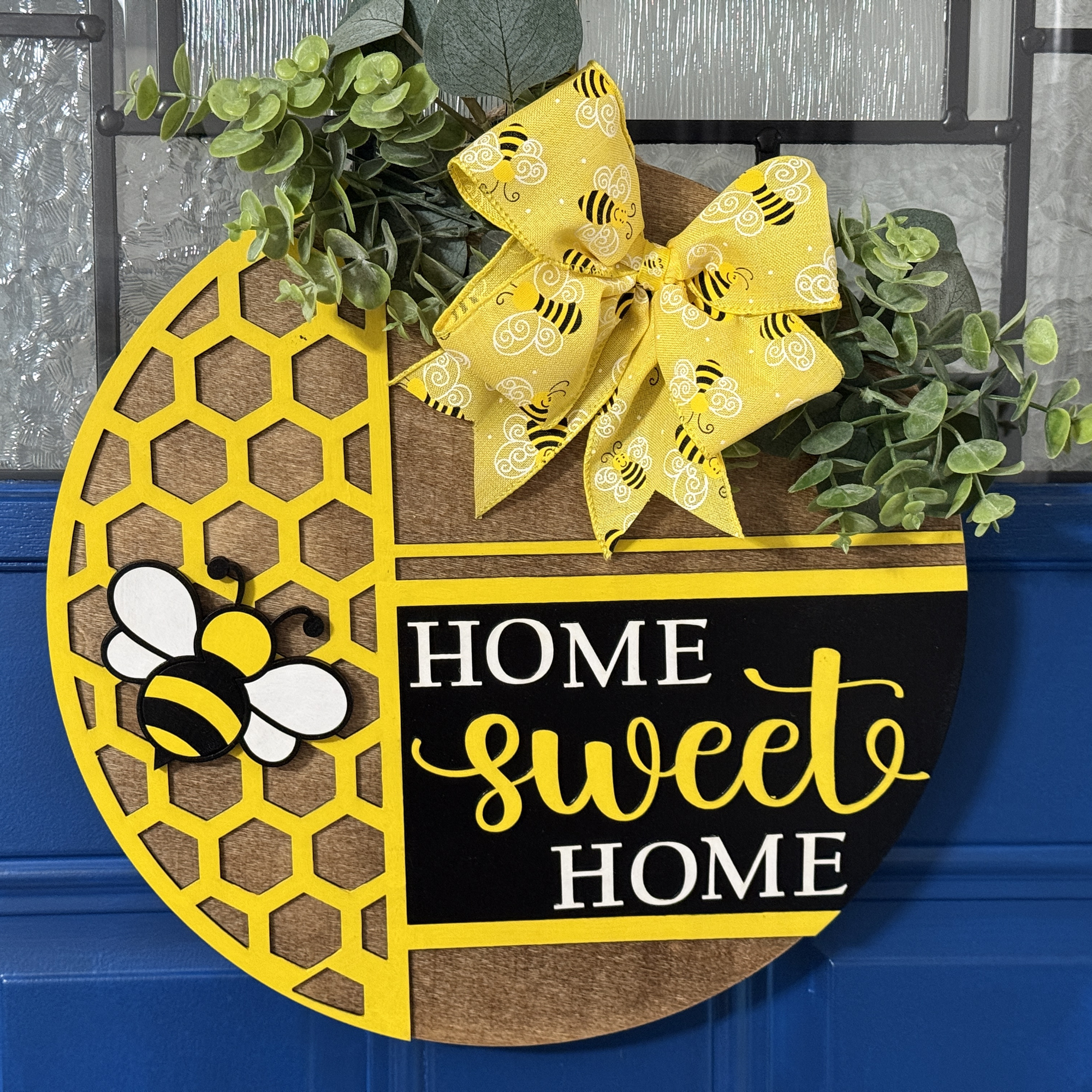 Home Sweet Home door hanger on stained base with black background, faux with greenery and coordinating bow