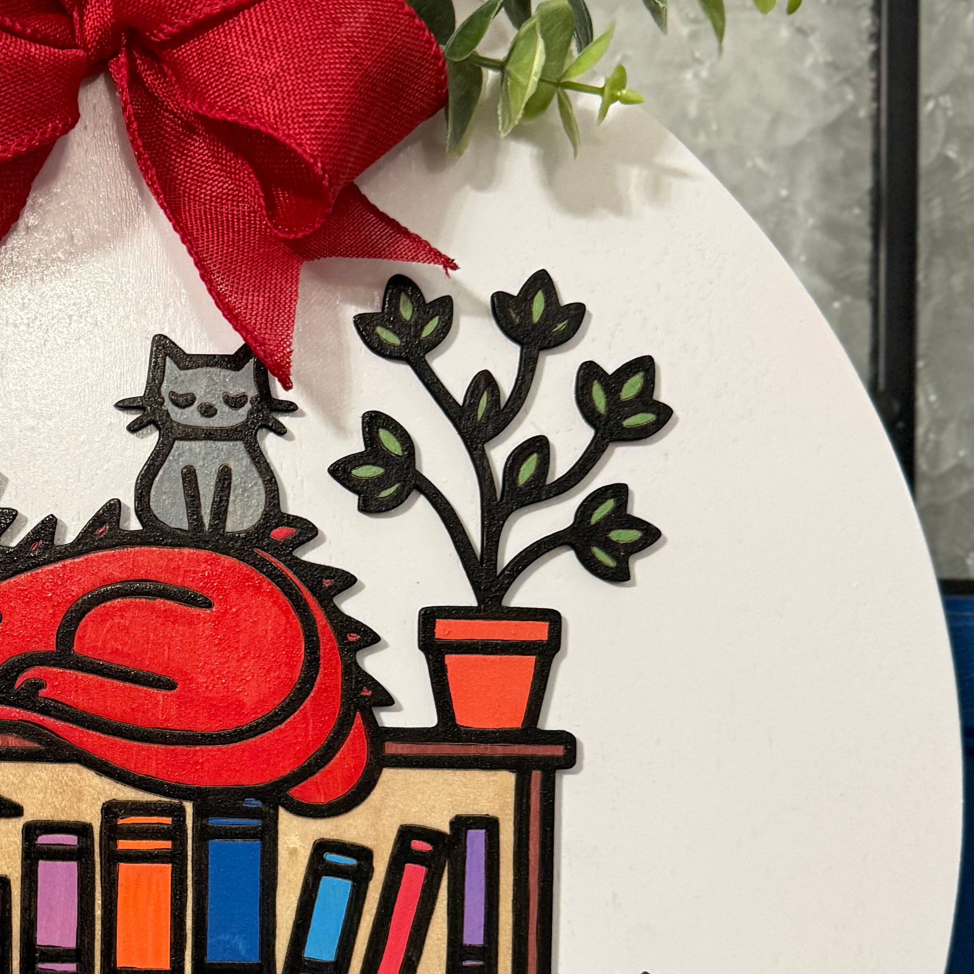 Close-up of red dragon curled on top of bookshelf with detailed painted scales