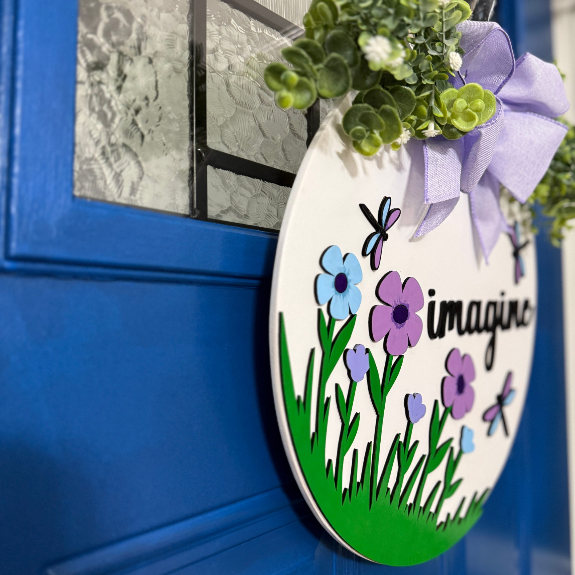 Angled side view of spring floral door hanger showing layered wood design and depth against a blue door