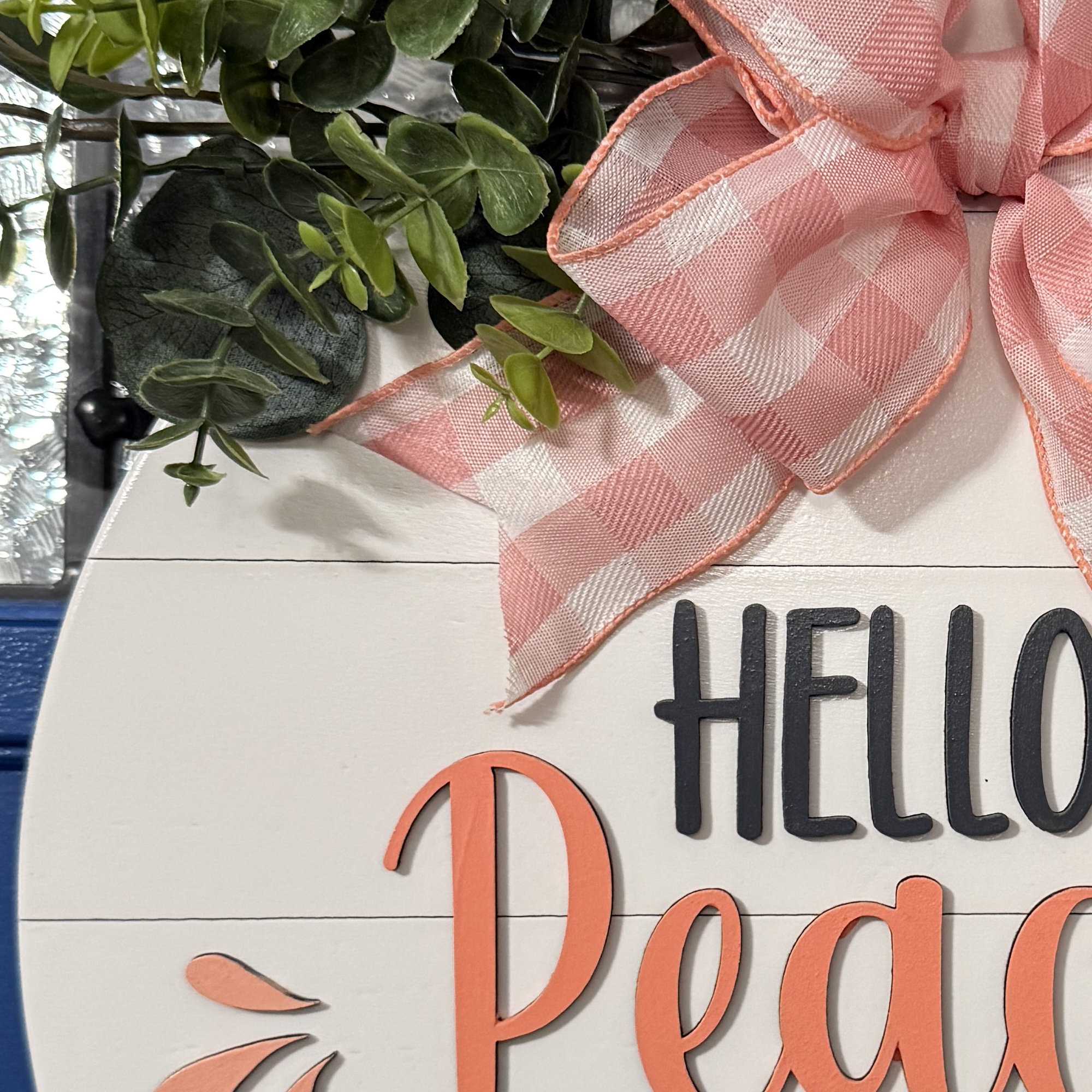 Close-up of pink gingham bow and layered greenery on Hello Peachy summer front door decor