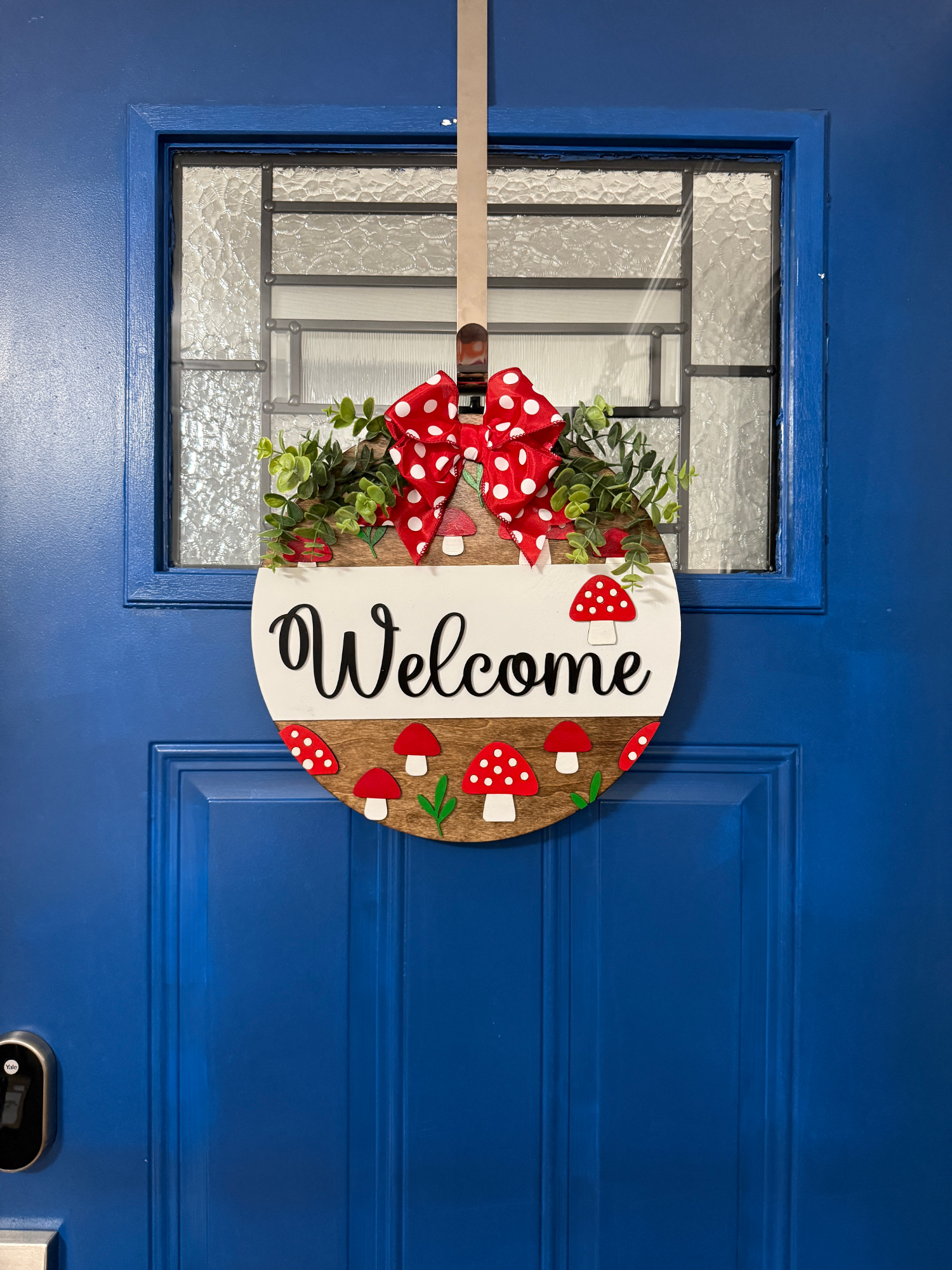 Round wood summer door hanger featuring red mushrooms and stained wood detail