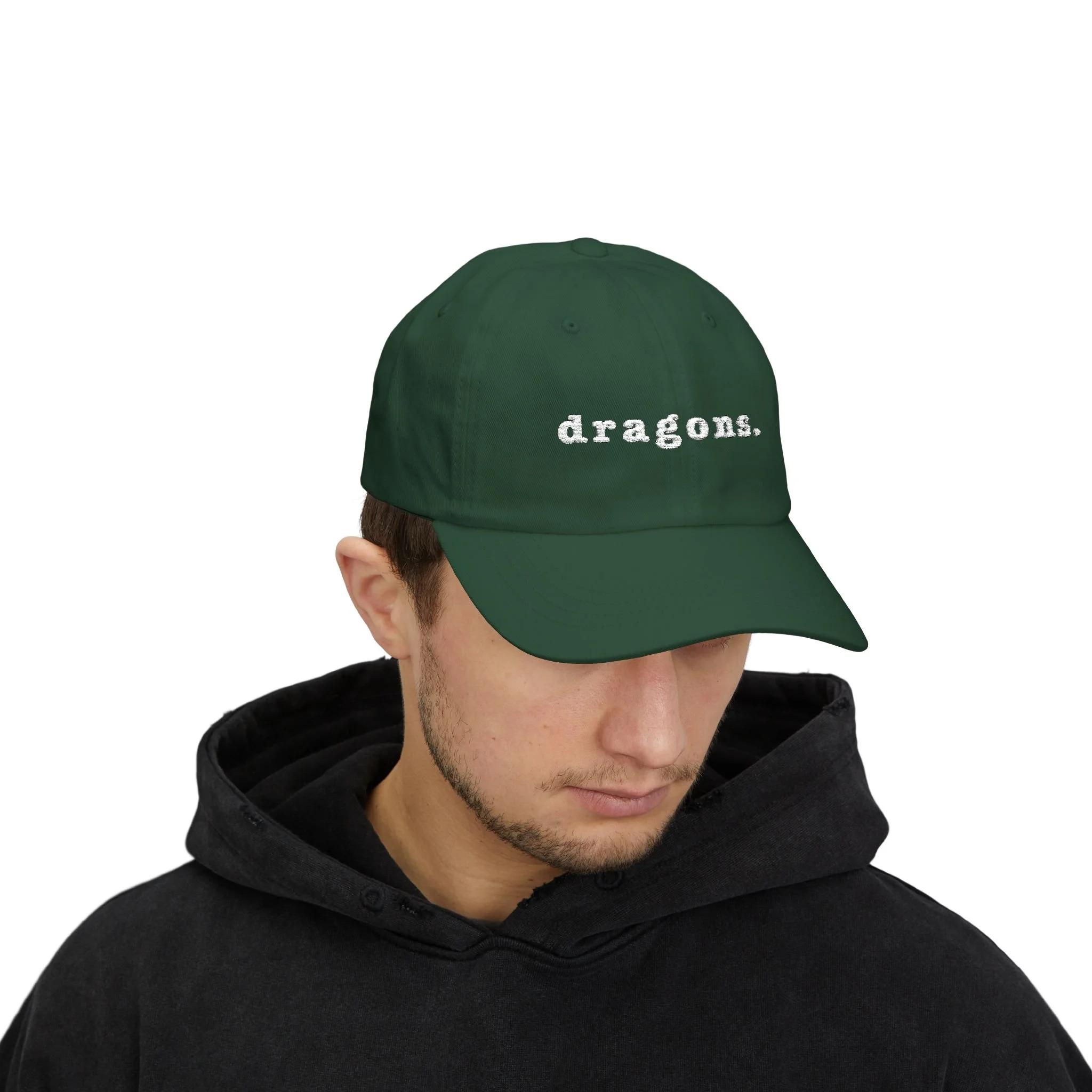 Model wearing spruce green dad cap with minimalist embroidered “dragons.” text on the front.