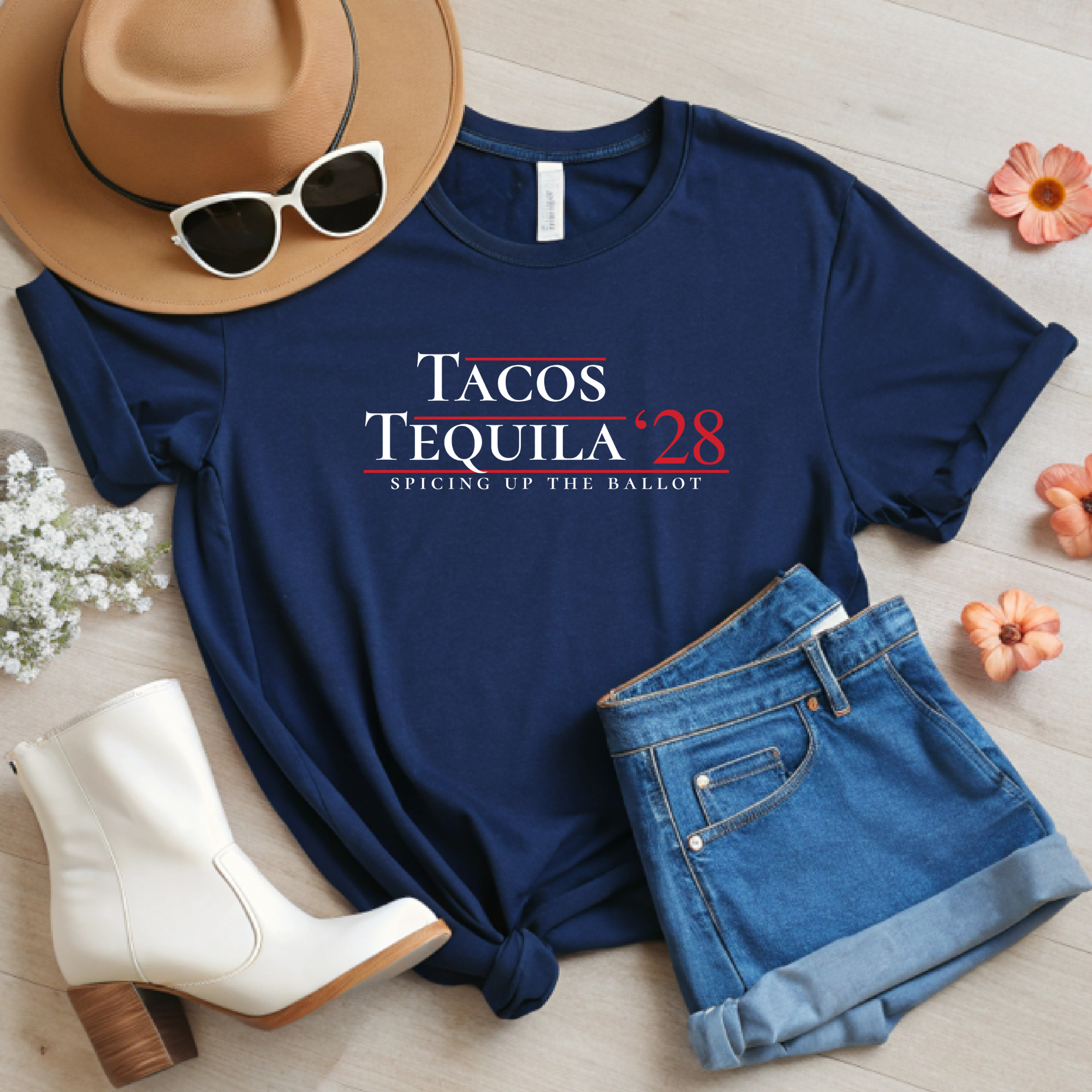 Navy Tacos & Tequila ’28 parody campaign tee styled with hat, sunglasses, denim shorts, and white boots on a light wood background