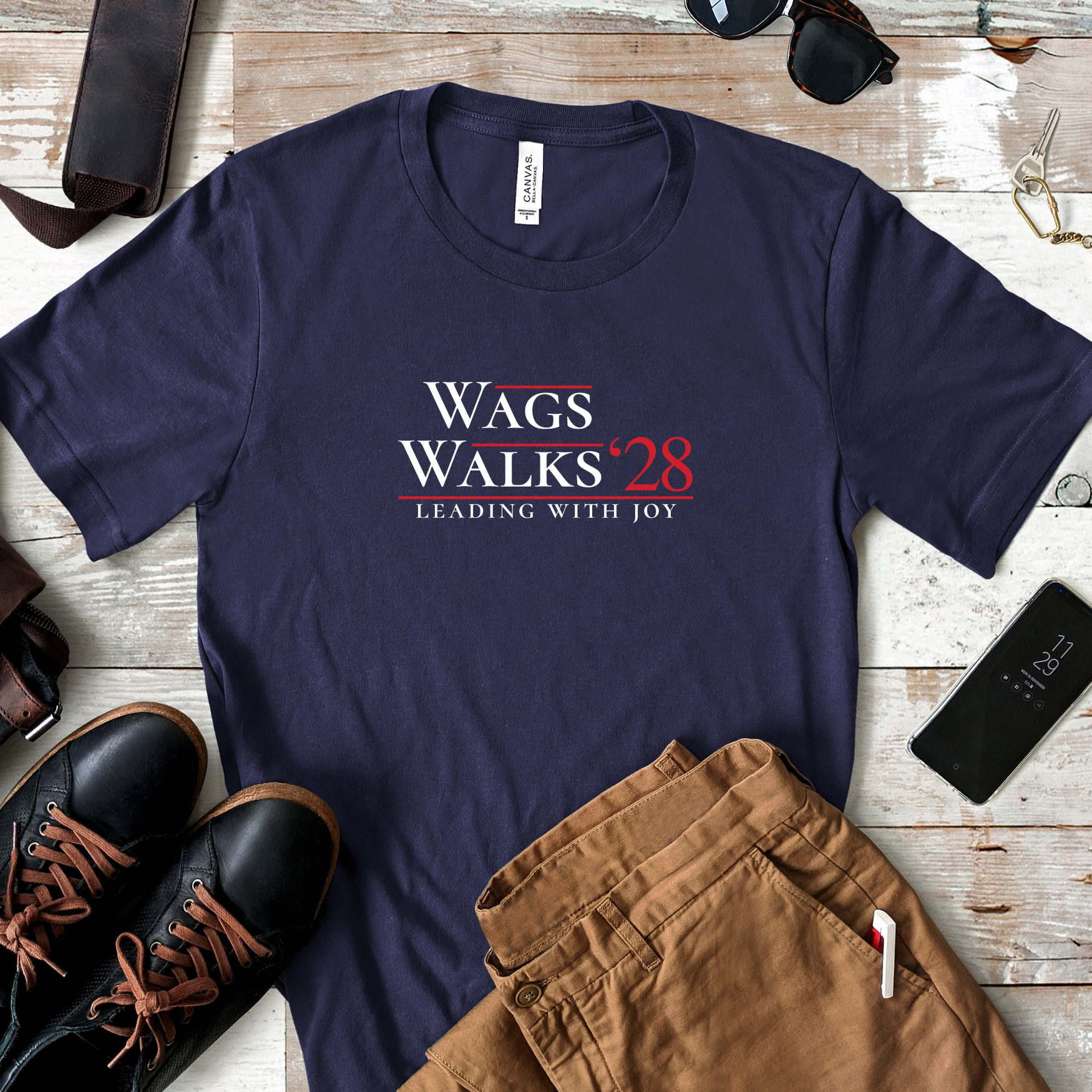 Flat lay of navy Wags Walks ’28 parody campaign tee styled with brown pants, boots, and accessories.