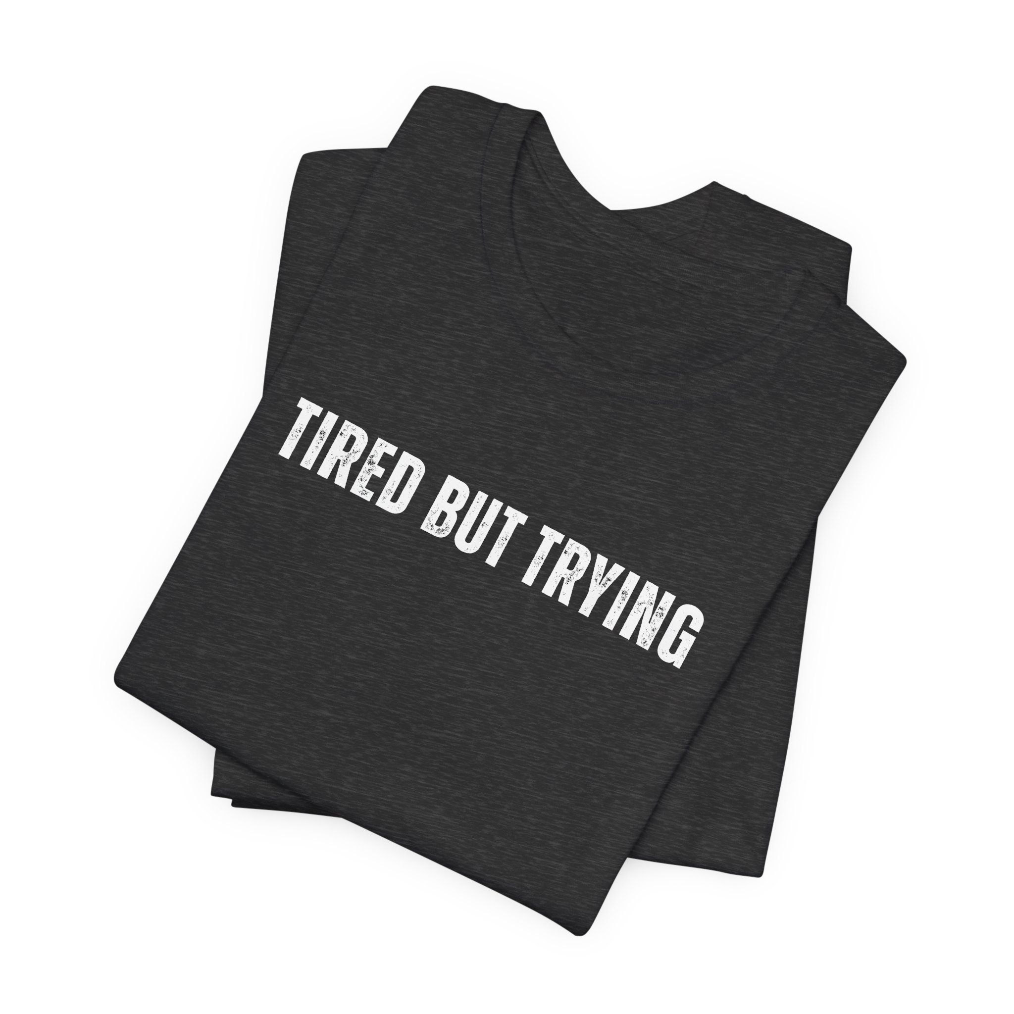 Folded dark heather gray t shirt with tired but trying phrase