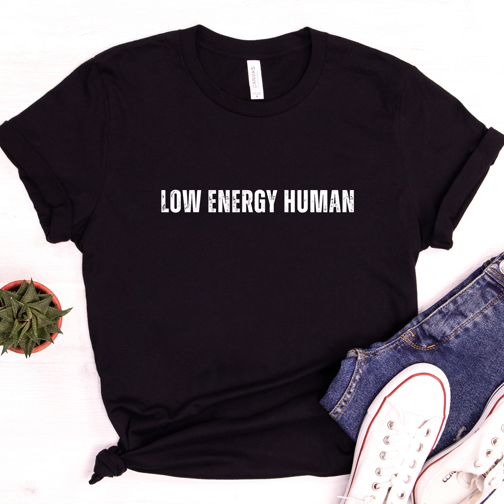 Womens black t shirt styled flat lay with low energy human lettering