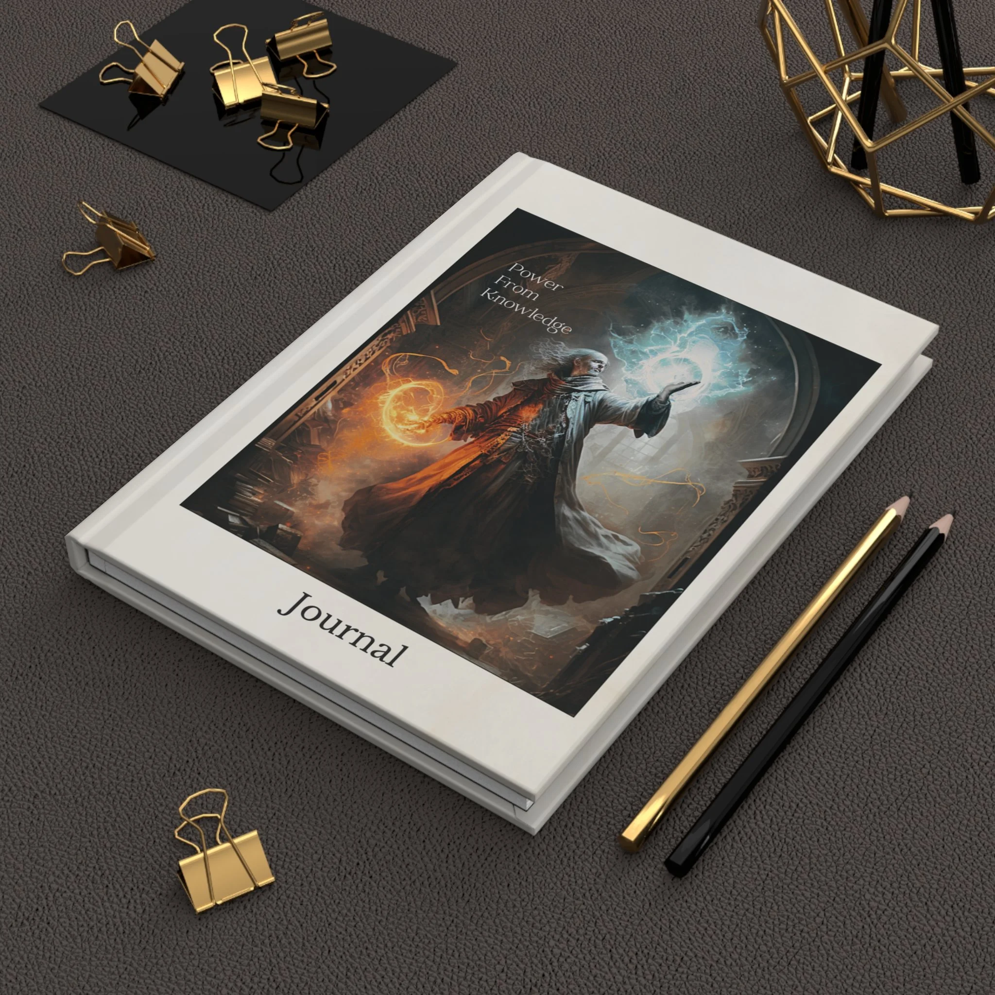 Angled tabletop view of Power From Knowledge fantasy journal with pencils and gold desk accessories