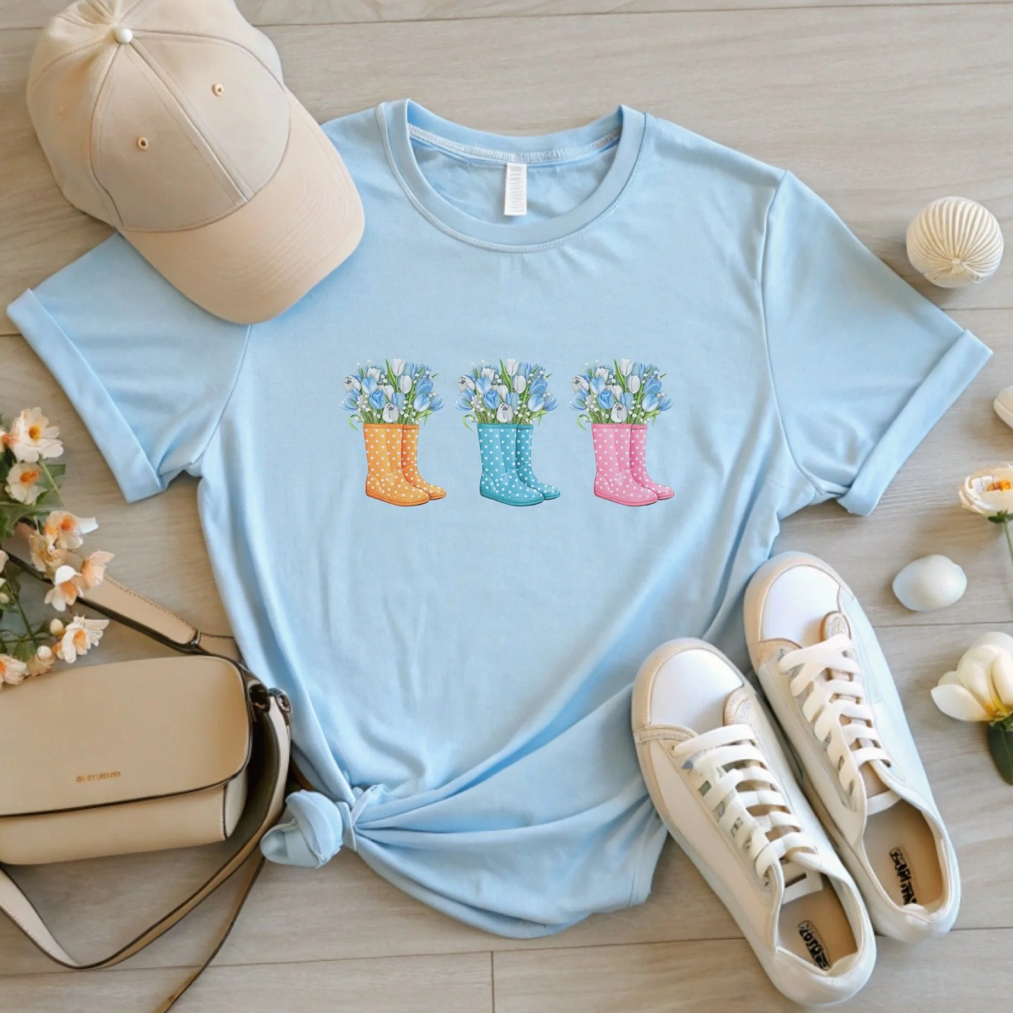 Daytime styled view of Floral Rain Boots graphic shirt on a baby blue tee with jeans, sneakers, and spring accessories