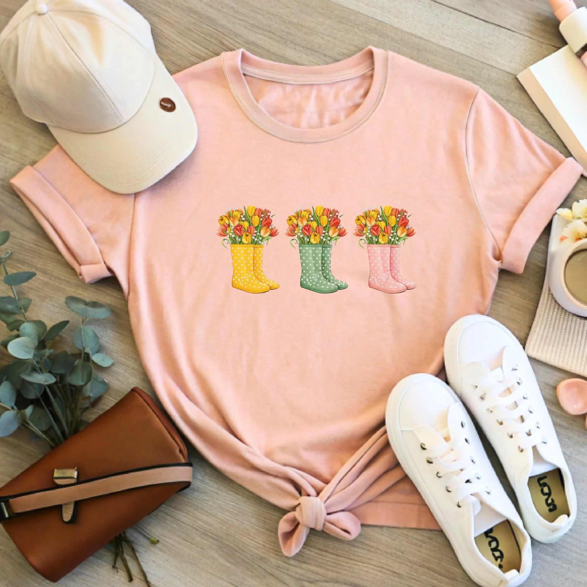 Daytime styled view of Floral Rain Boots graphic shirt on a peach tee with jeans, sneakers, and spring accessories