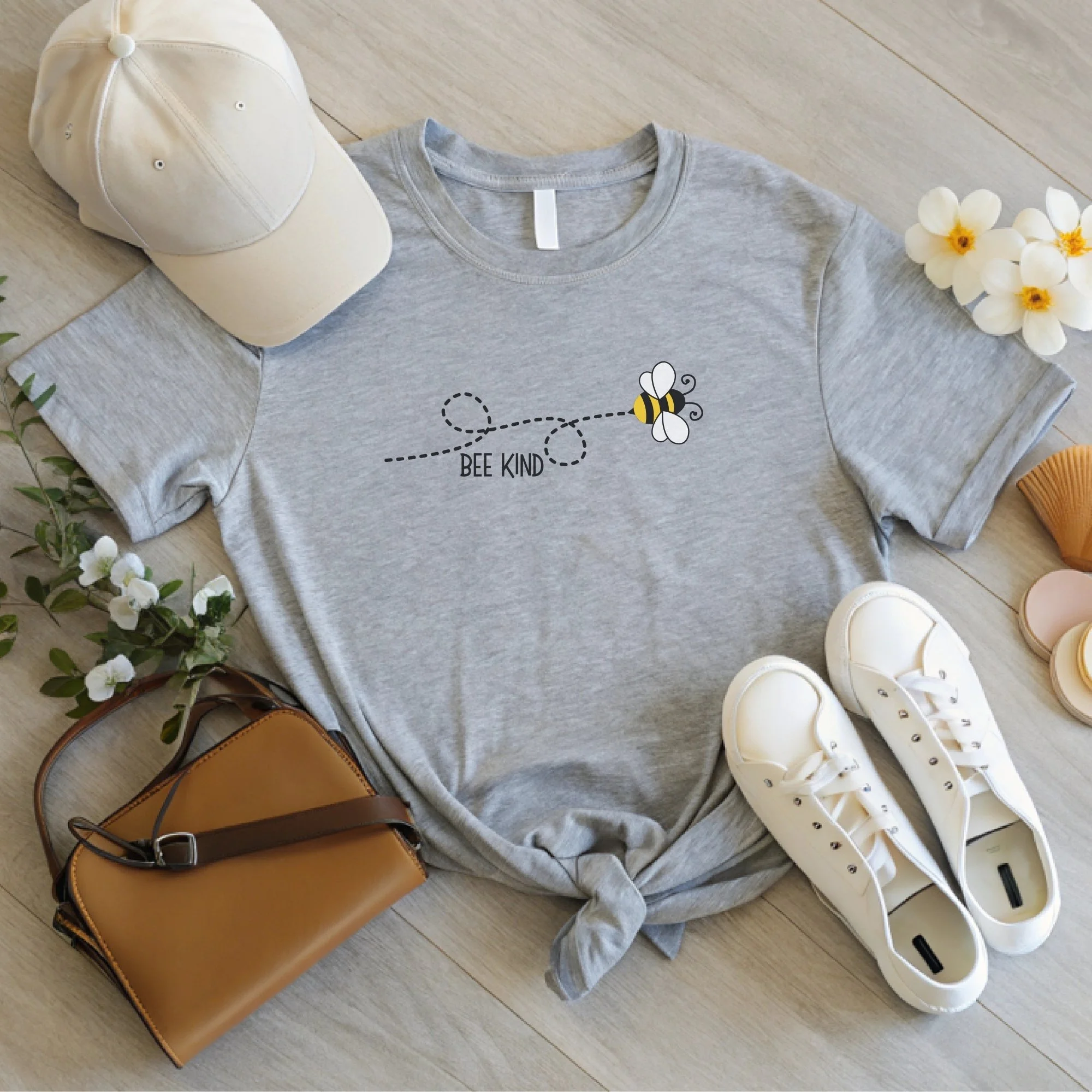Daytime styled view of Bee Kind graphic shirt on heather dust tee with jeans, sneakers, and spring accessories