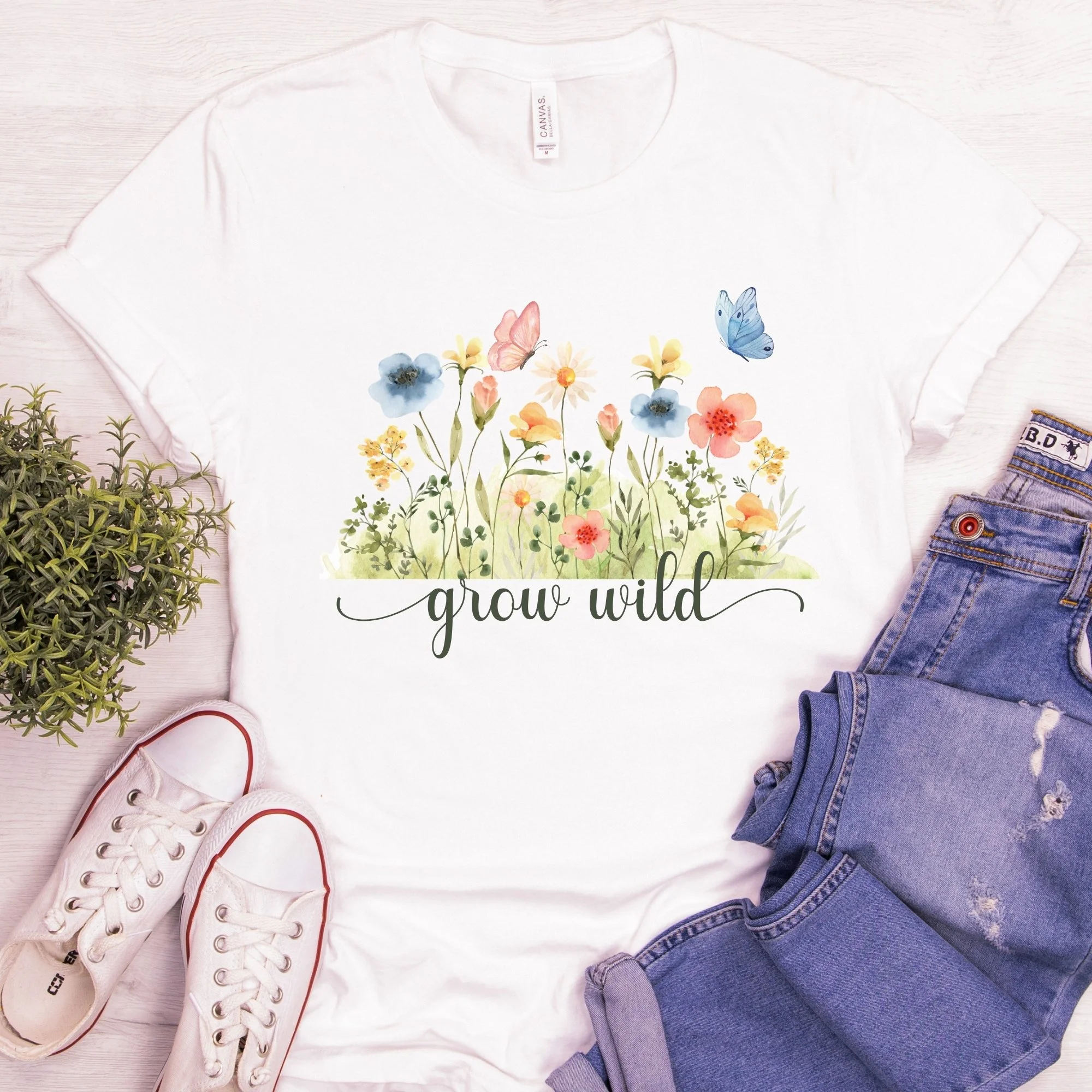 Daytime styled view of Grow Wild graphic shirt on natural cream tee with jeans, sneakers, and spring accessories