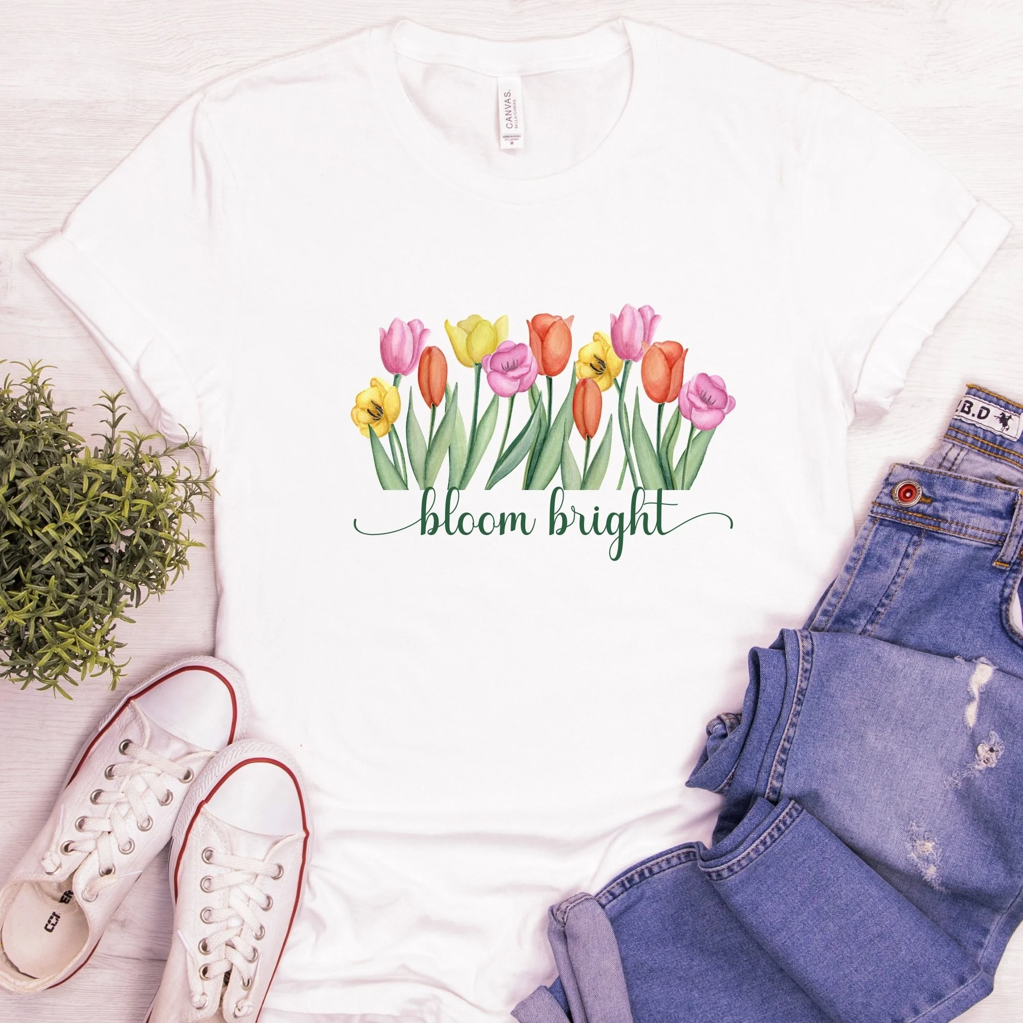 Daytime styled view of Bloom Bright graphic shirt on white tee with jeans, sneakers, and spring accessories