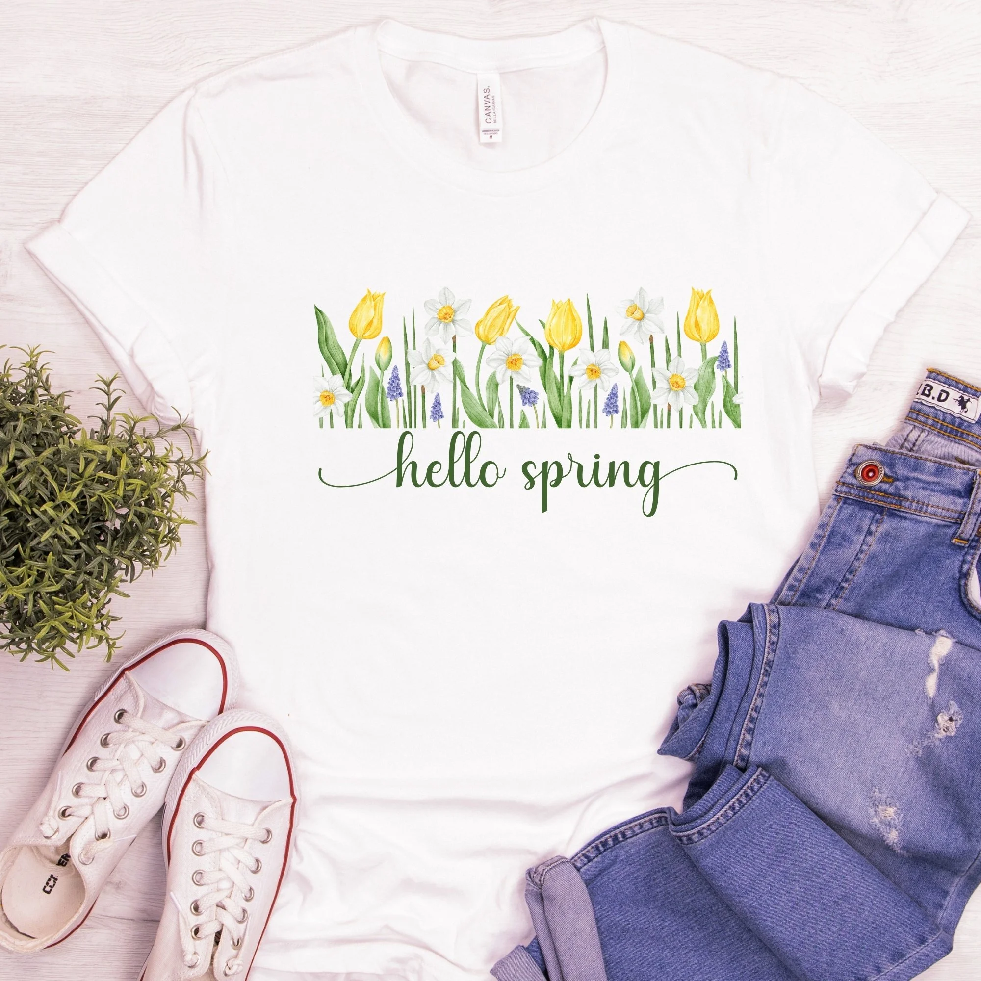 Daytime styled view of Hello Spring graphic shirt on white tee with jeans, sneakers, and spring accessories