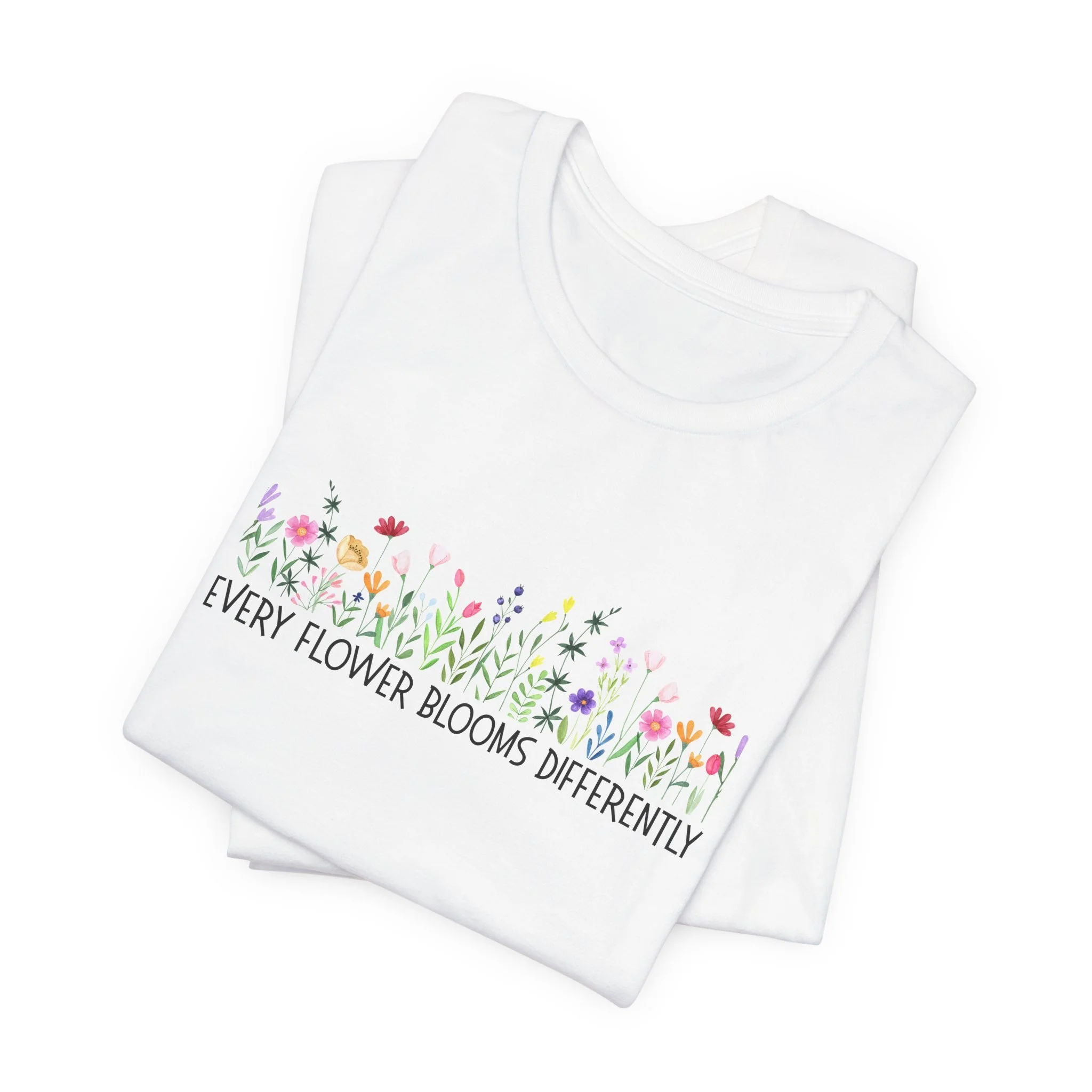Folded white t-shirt featuring Every Flower Blooms Differently graphic
